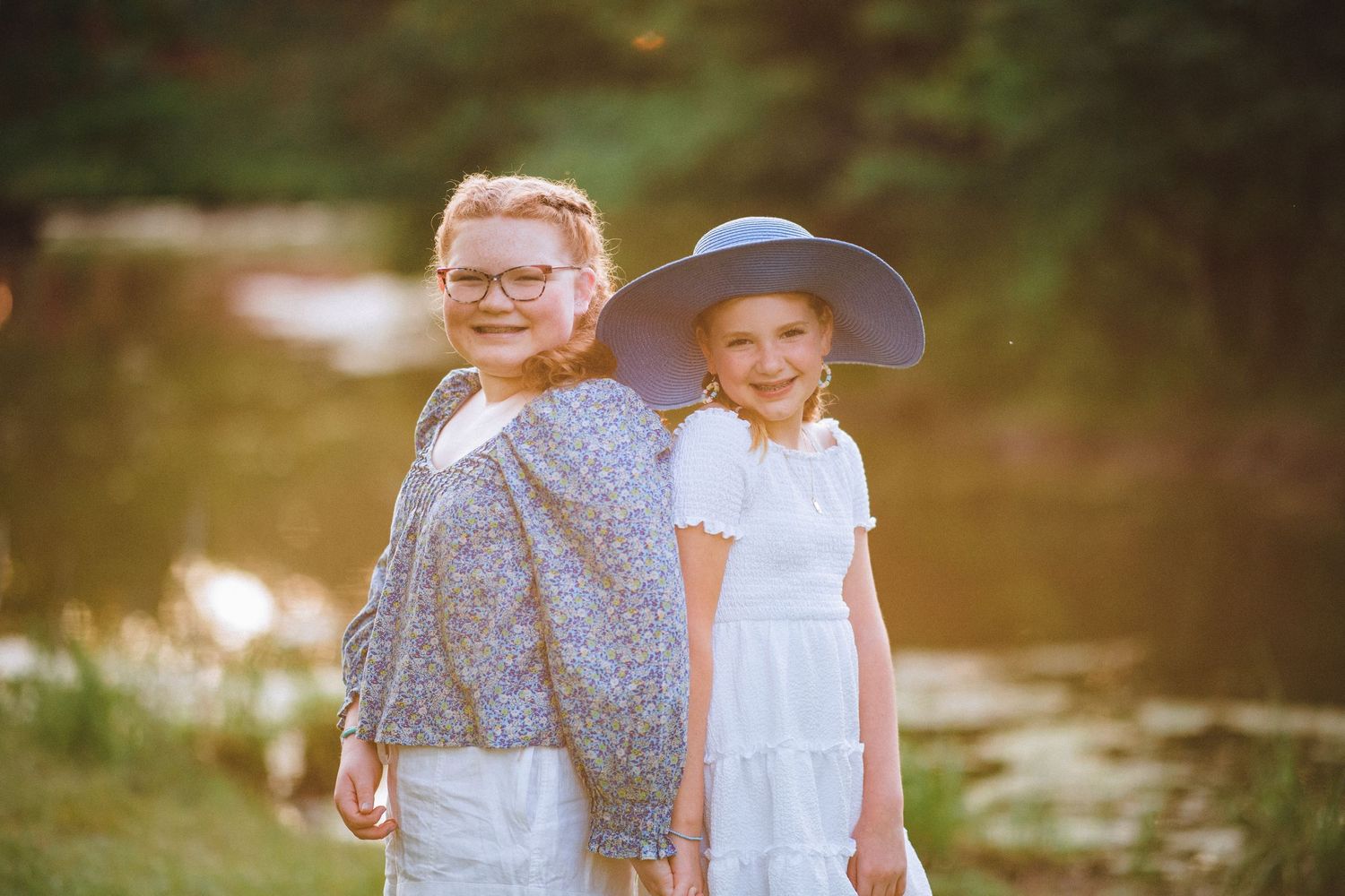 Sisters holding hands with their backs together at a beautiful park in Indiana