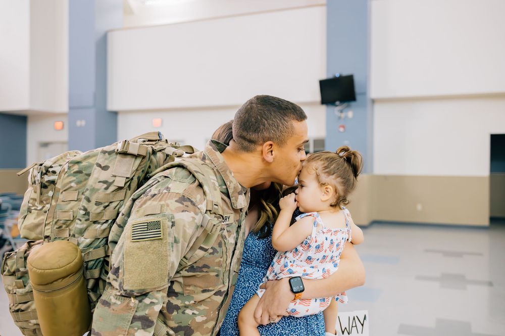 Emotional military homecoming moment between soldier and family members.