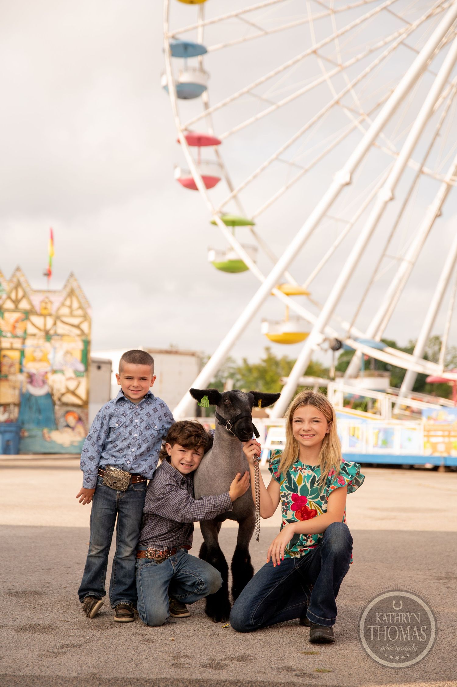 A family poses with their pet in front of a towering ferris wheel at a carnival.