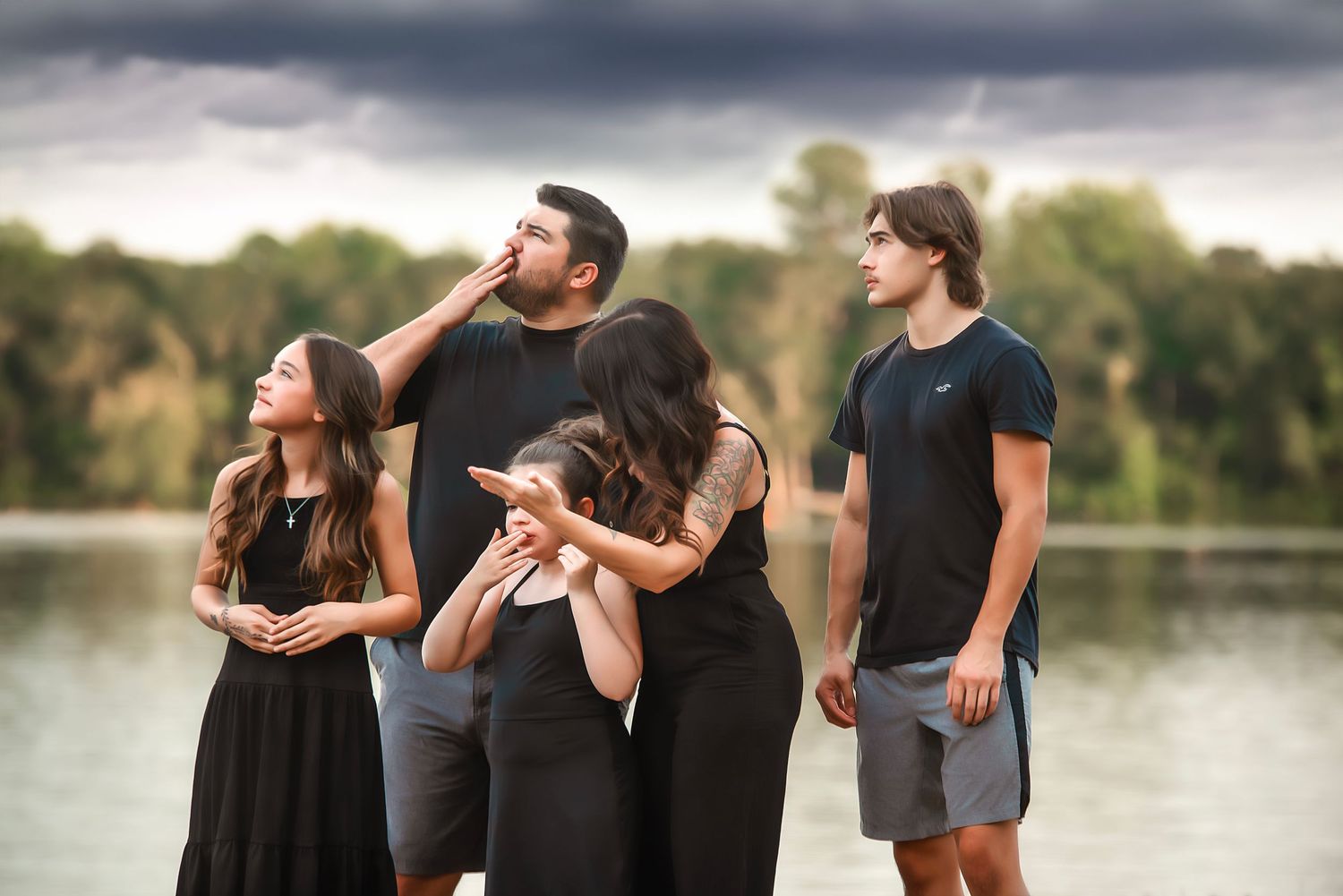 A group poses dramatically against a stormy sky beside a reflective lake. remembrance sessions