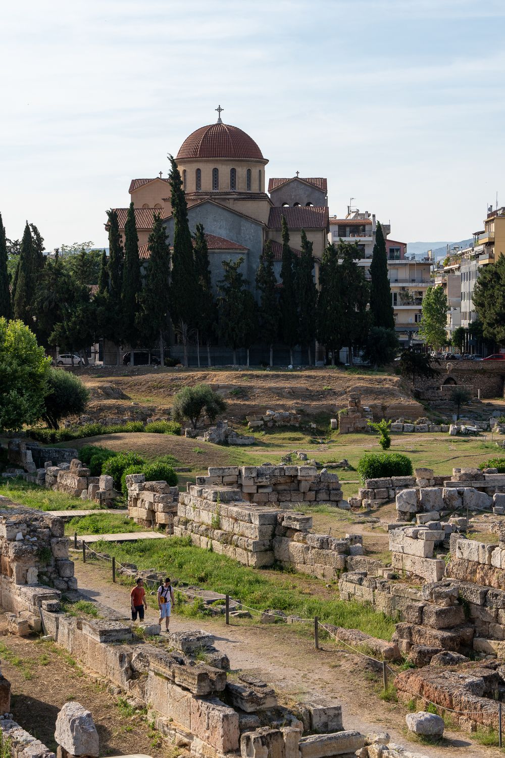 Byzantine church with red dome overlooking ancient ruins and archaeological site.
