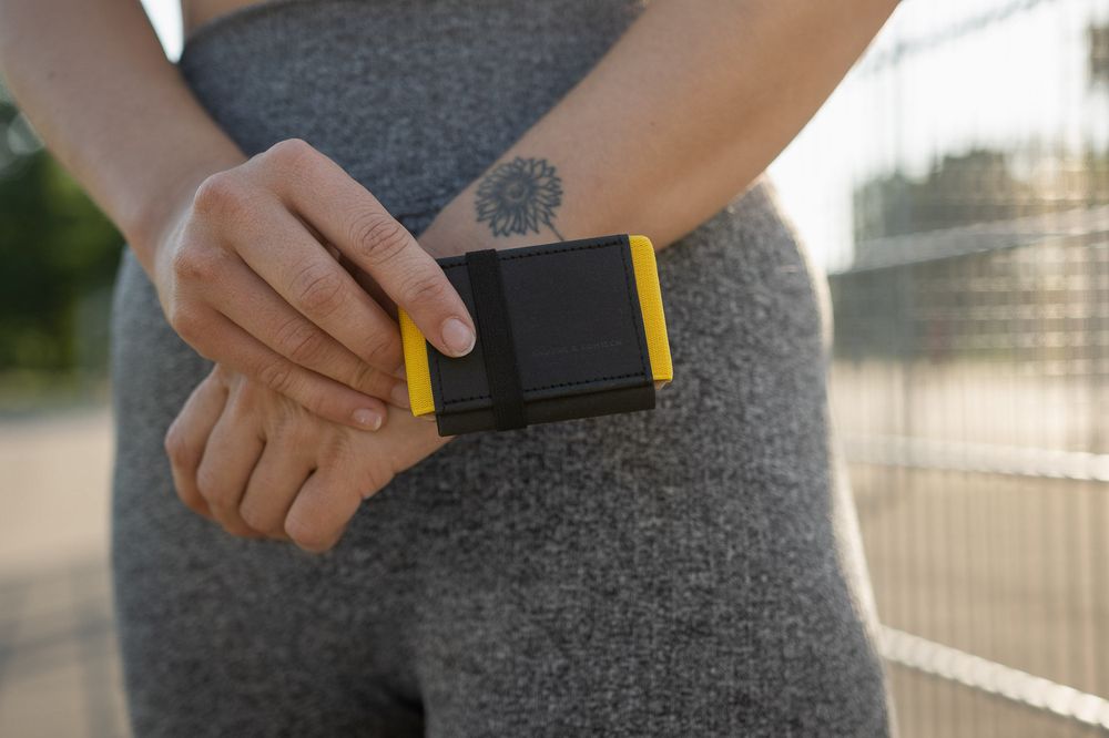 Close-up of person wearing gray workout pants with a small fitness tracking device in hand during outdoor exercise.