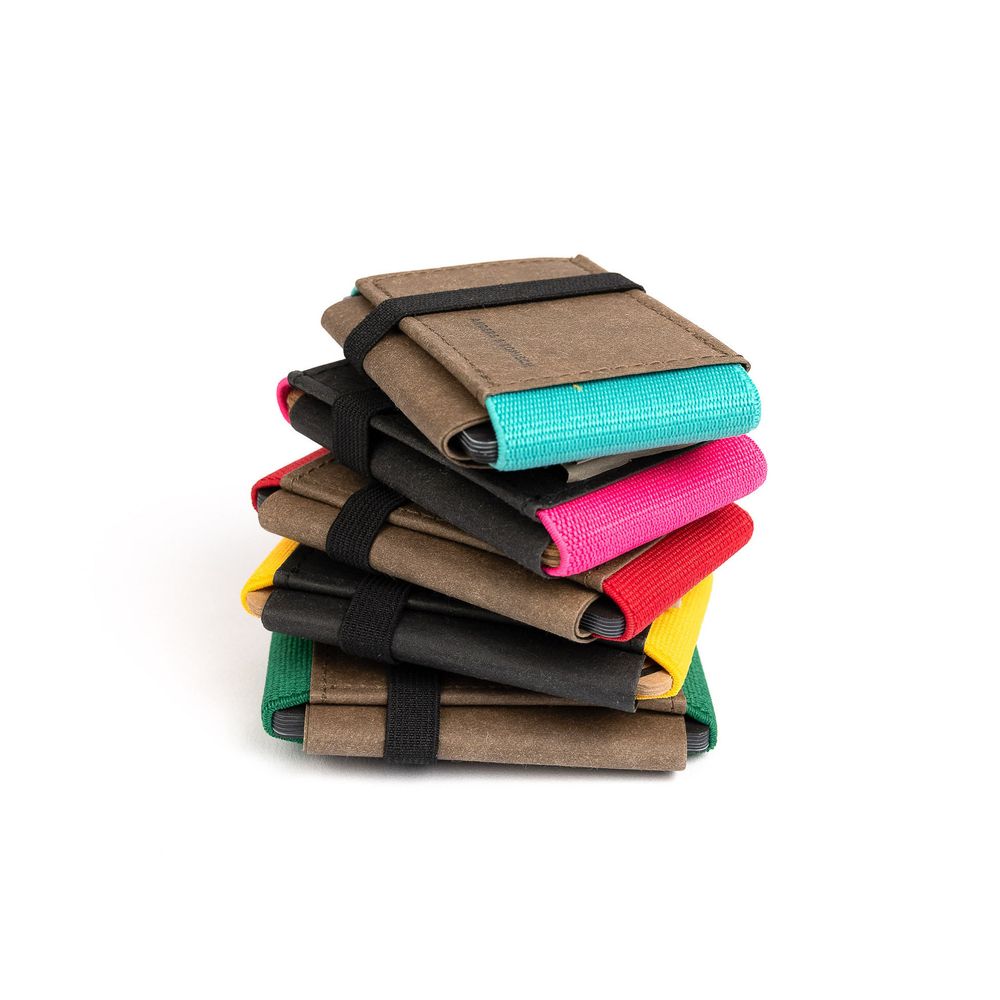Stack of colorful minimalist card wallets made from brown kraft paper and elastic straps in various bright hues.