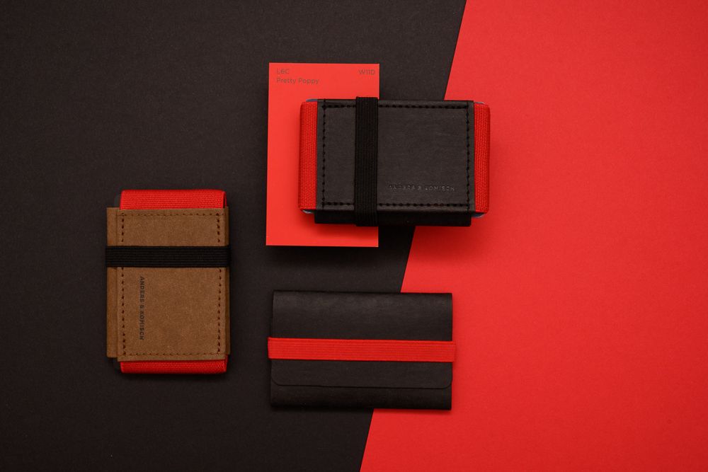 Minimalist leather wallets in brown and black colors displayed on a red and black background.