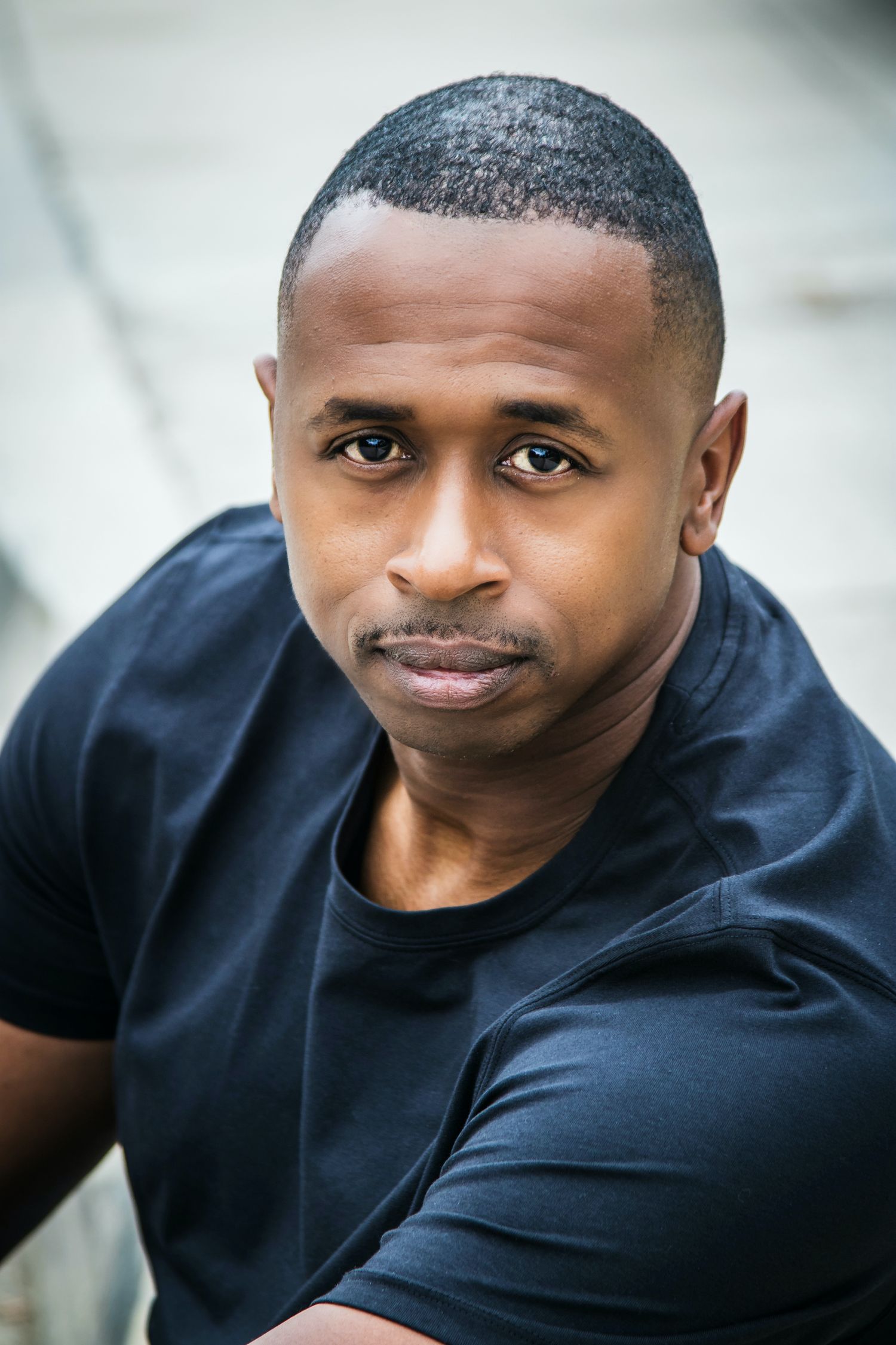 Professional headshot of a person in a black t-shirt against a light background.