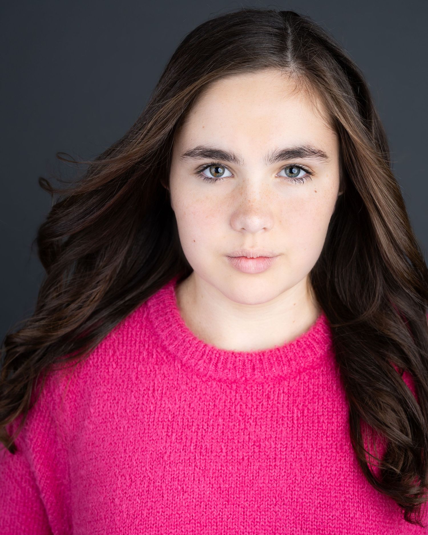 A series of portrait photos showing someone with long dark hair wearing a bright pink sweater against a dark background.