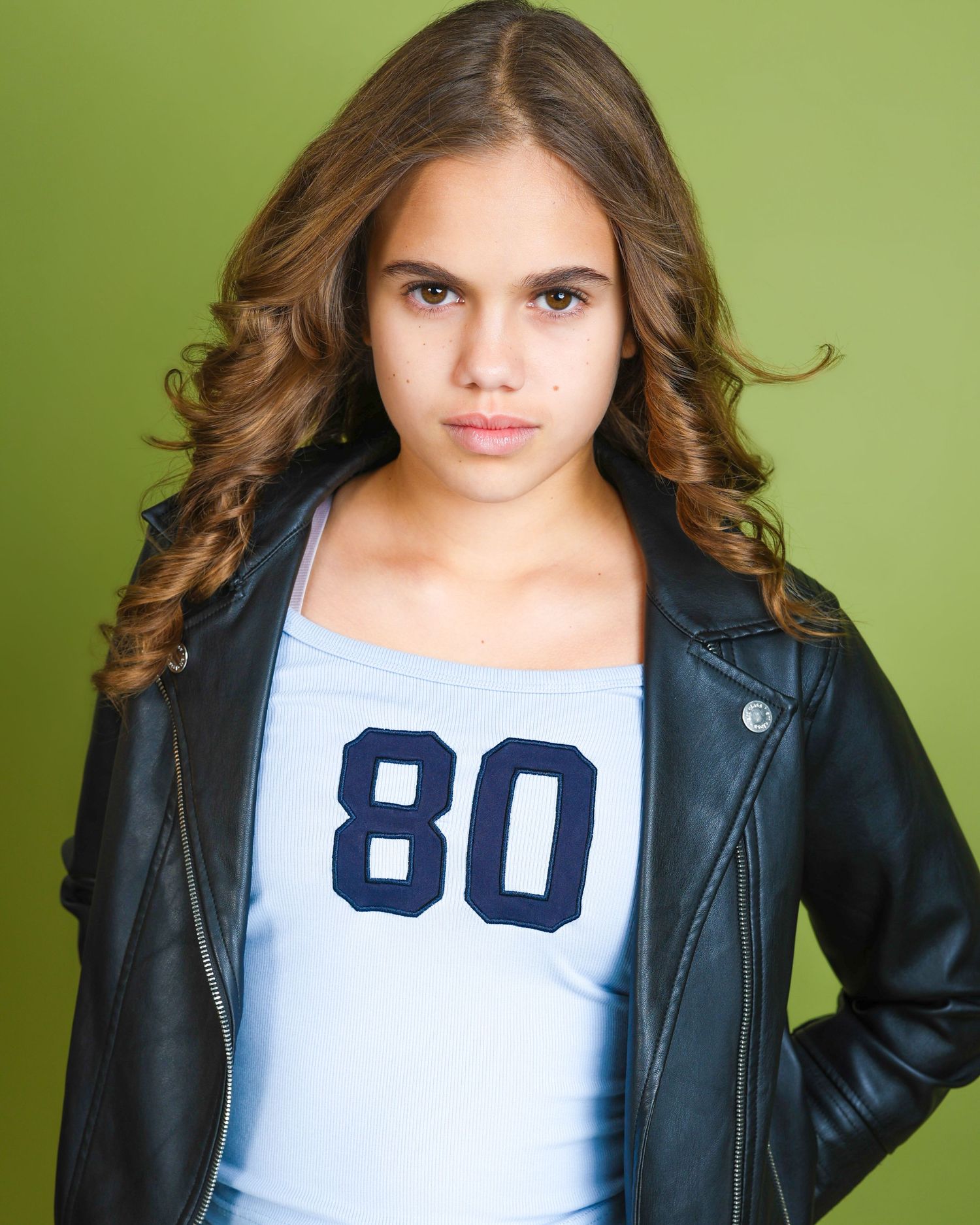 Person in a black leather jacket and white shirt against a lime green background.