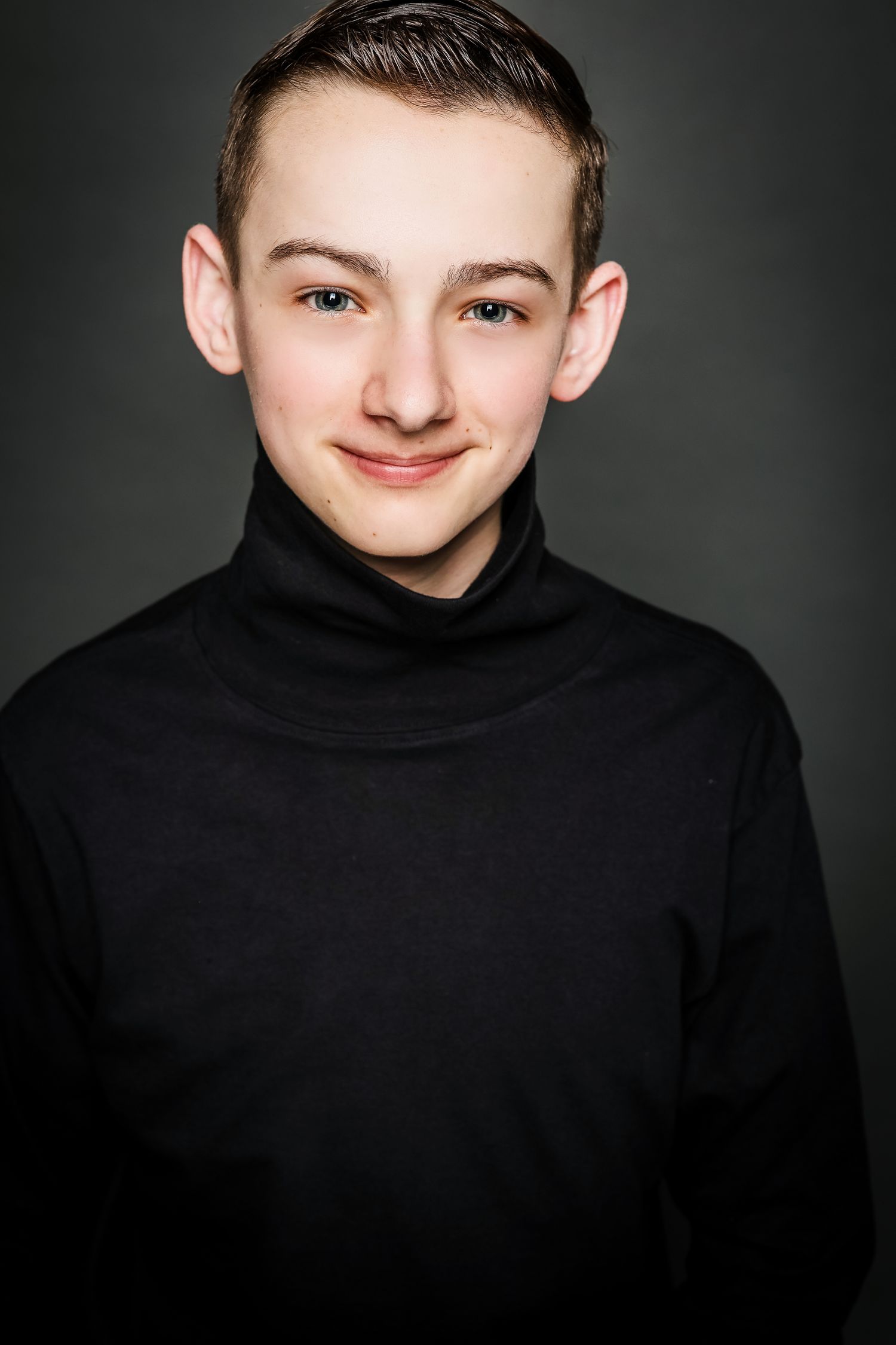 Professional headshot portrait of a young person wearing a black turtleneck sweater against a dark background.