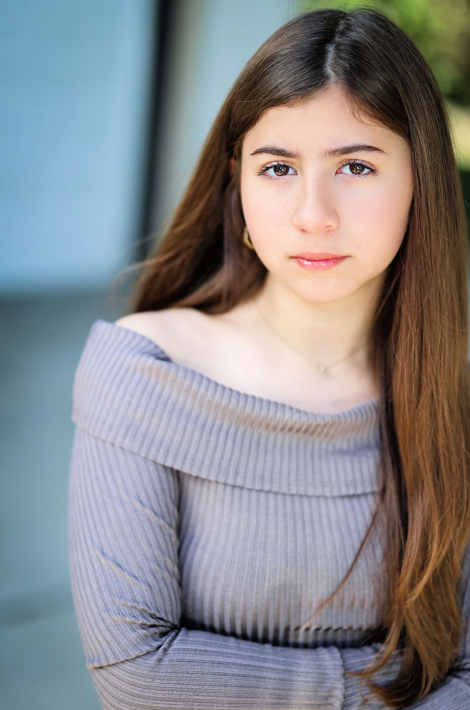 Virgina Actor Professional Headshot in gray off-shoulder sweater with long straight hair against blue background.