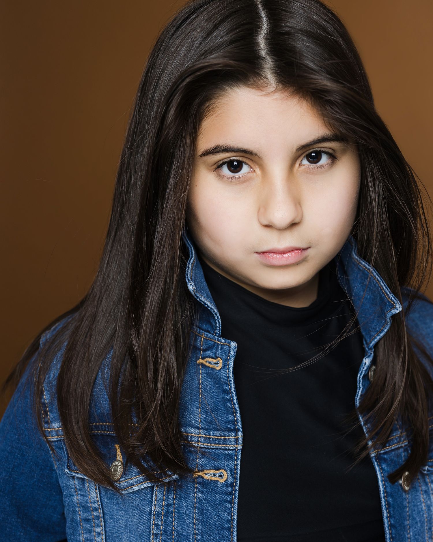 A series of portrait shots showing dark-haired youth wearing a denim jacket and black top against a brown background.