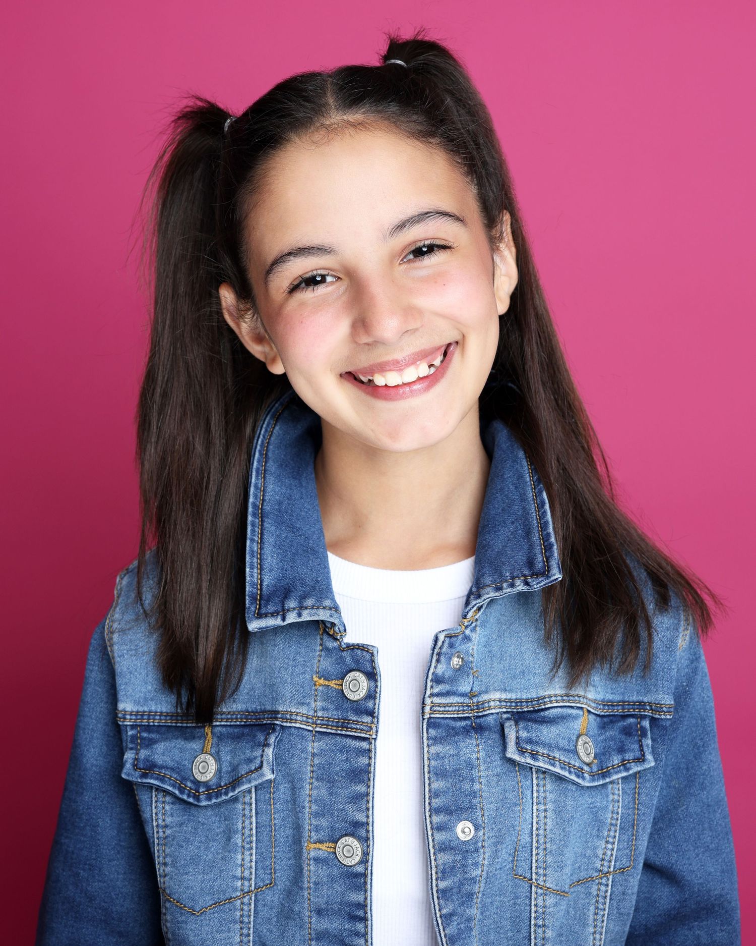 A series of expressive headshots against a bright pink background showing warmth and joy while wearing denim and white.