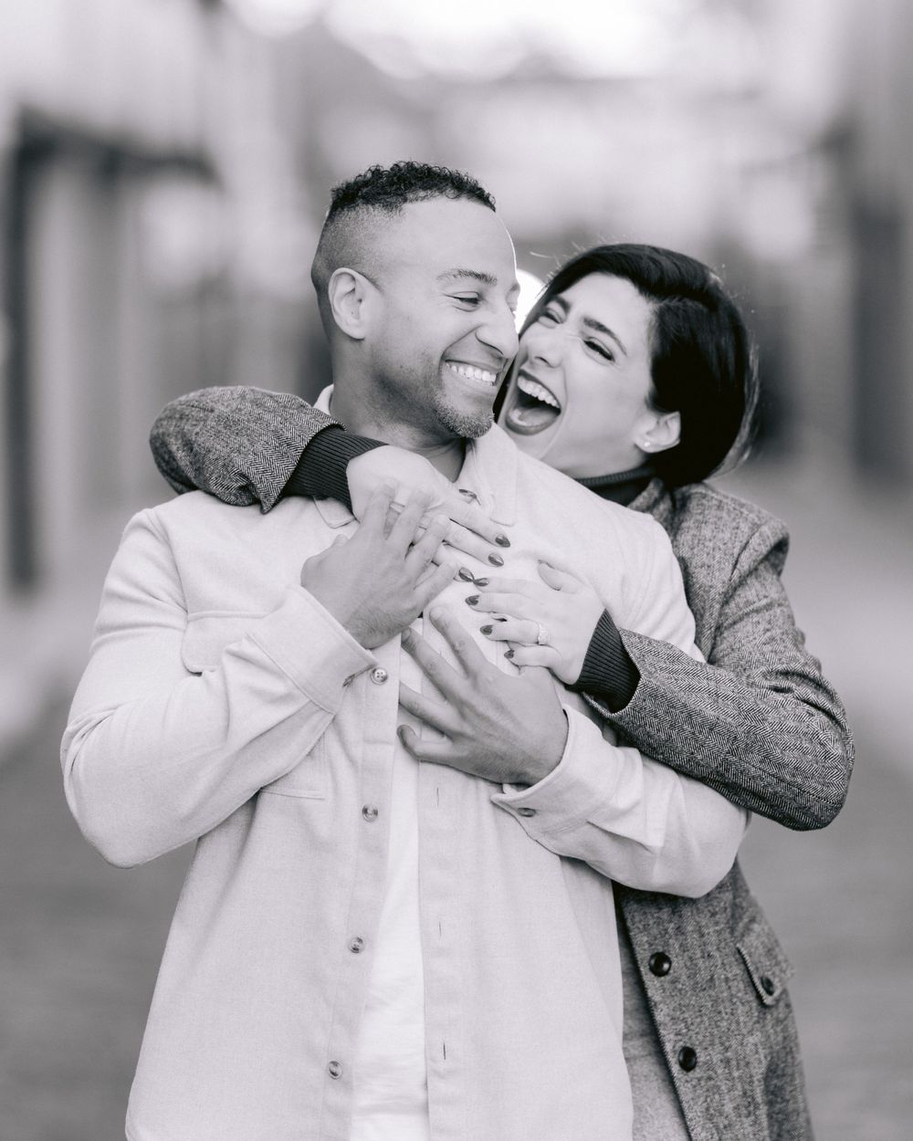 A joyful black and white portrait of a couple embracing and laughing together.
