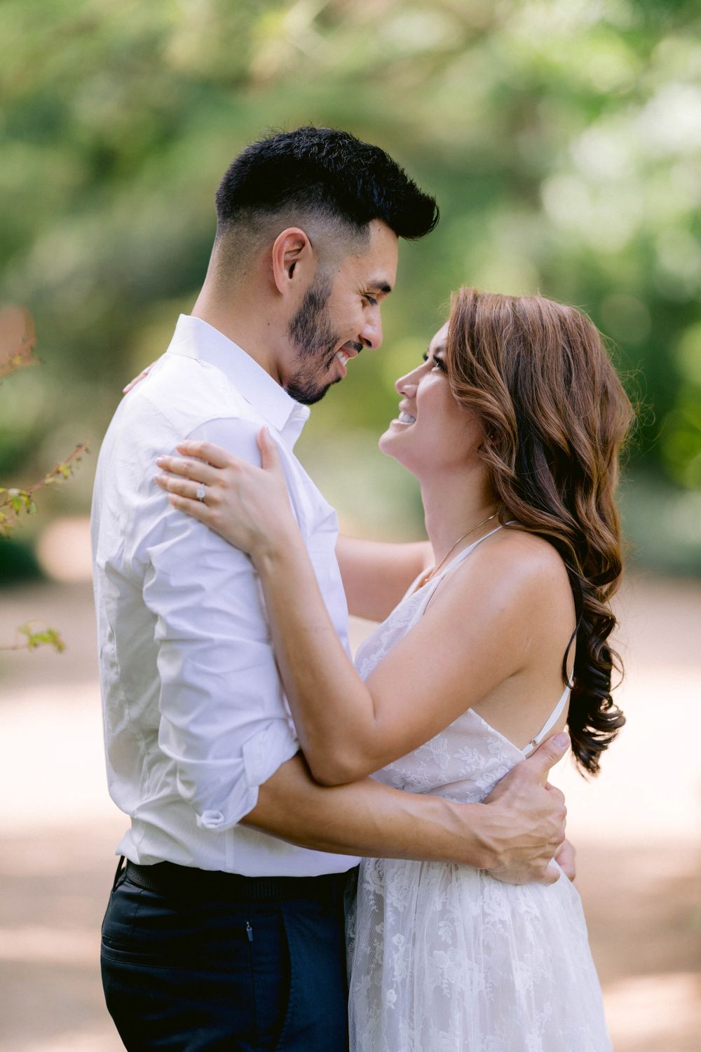 Couple sharing an intimate moment outdoors with soft natural lighting and greenery.
