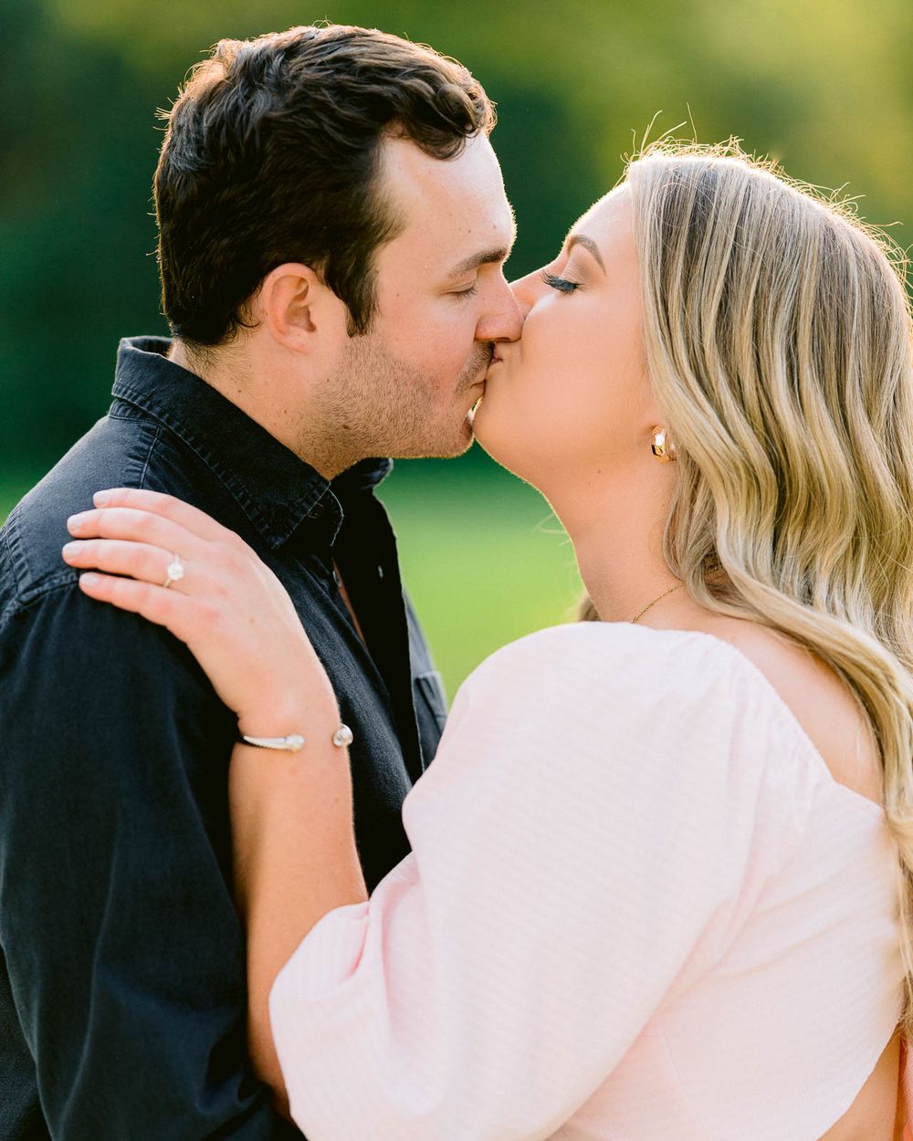 An intimate engagement photo showing a couple sharing a tender kiss outdoors.