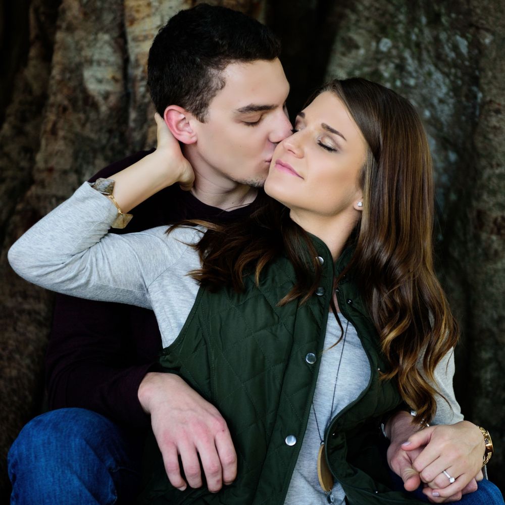 An intimate moment captured between a couple against a tree trunk background.