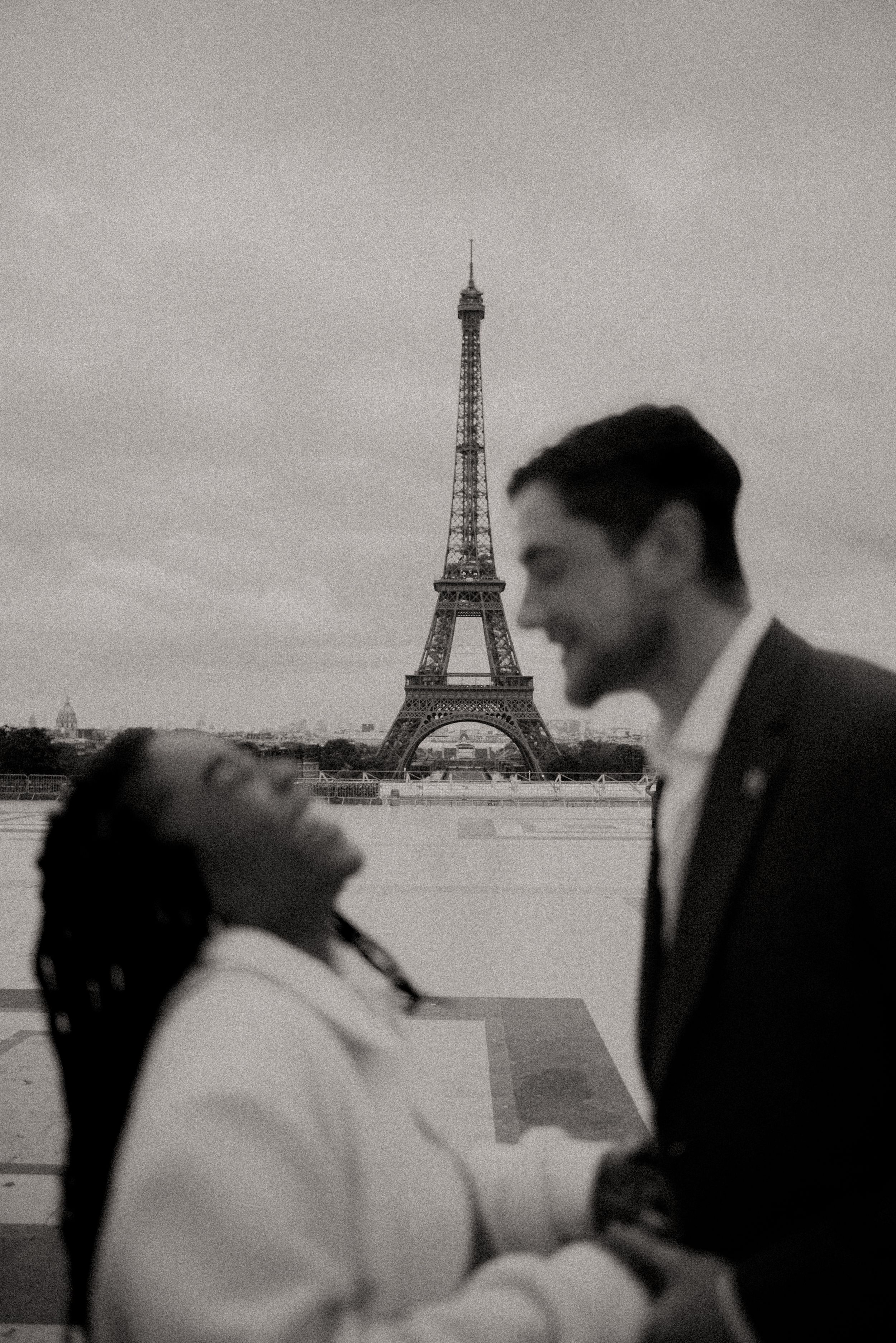 A couple laughs together during an intimate moment in front of the Eiffel Tower.