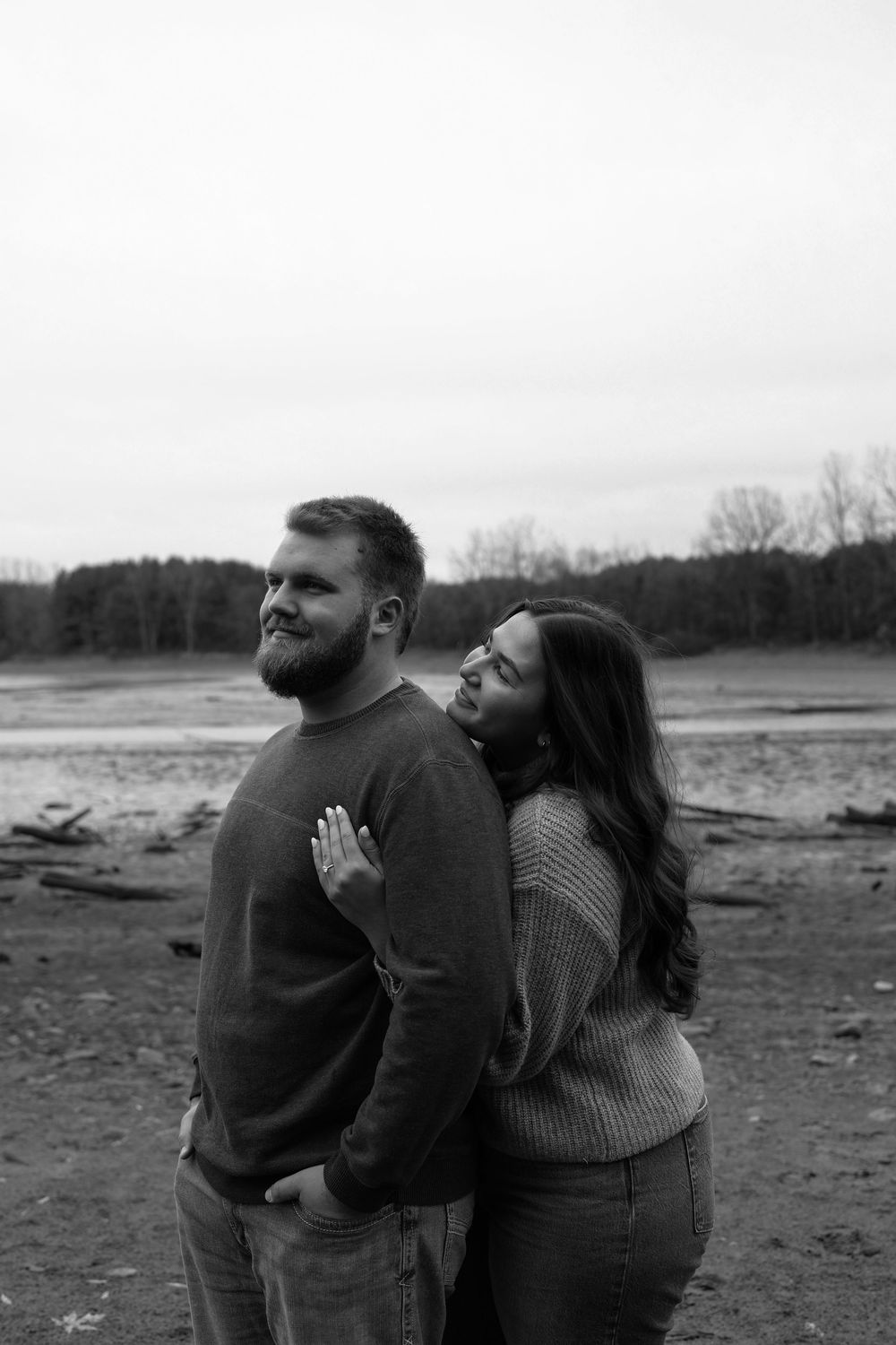 A romantic black and white photo series showing a couple embracing in a winter field landscape.