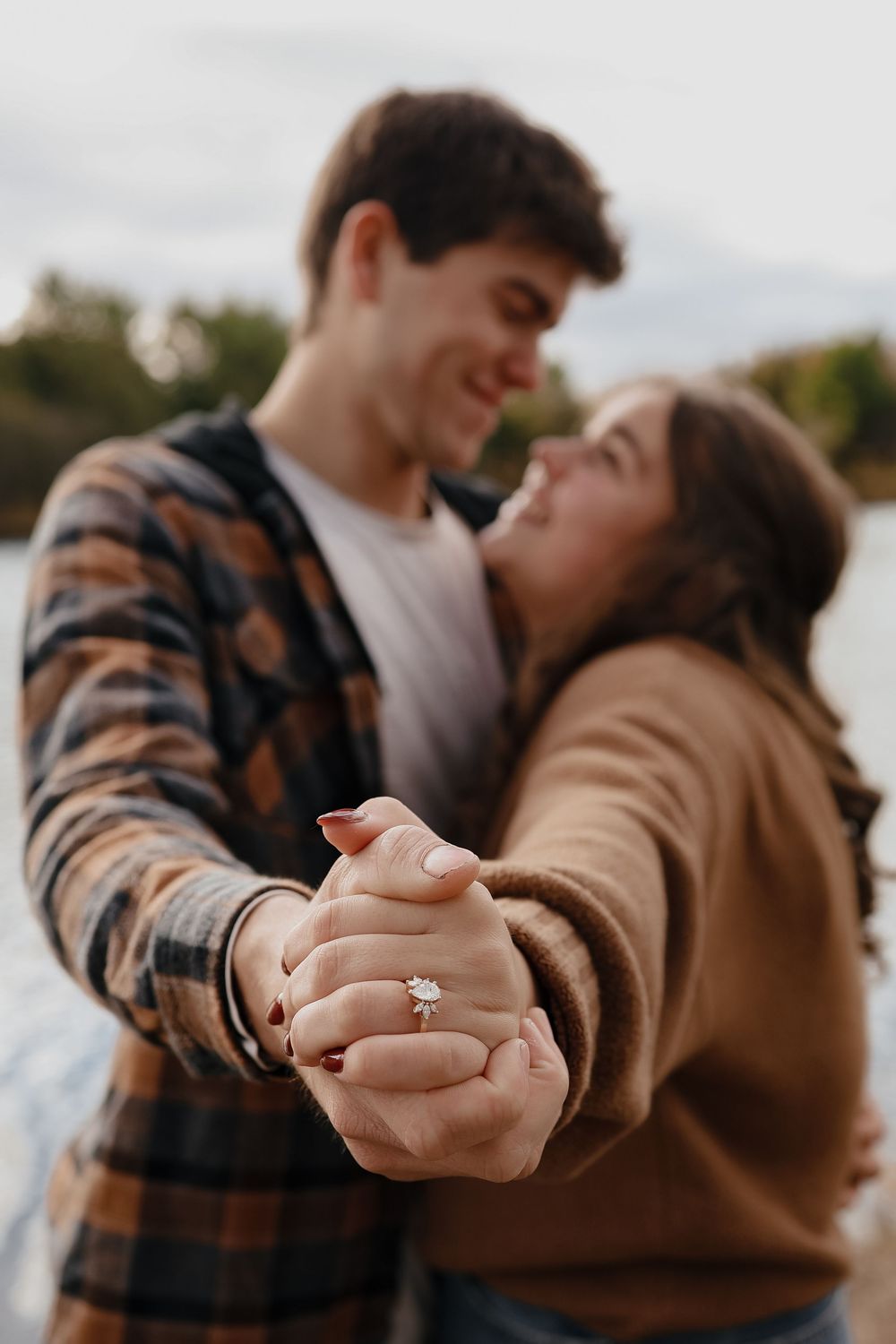 Romantic engagement photoshoot showing couple embracing and dancing while displaying diamond ring on hand.