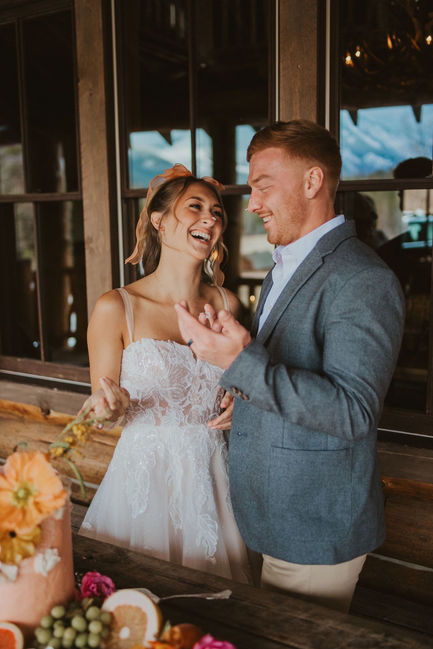wedding picture of a couple cutting the cake and putting frosting on eachothers noses