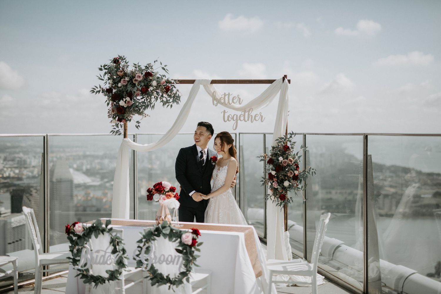 Modern rooftop wedding ceremony with white floral arch and ocean views.