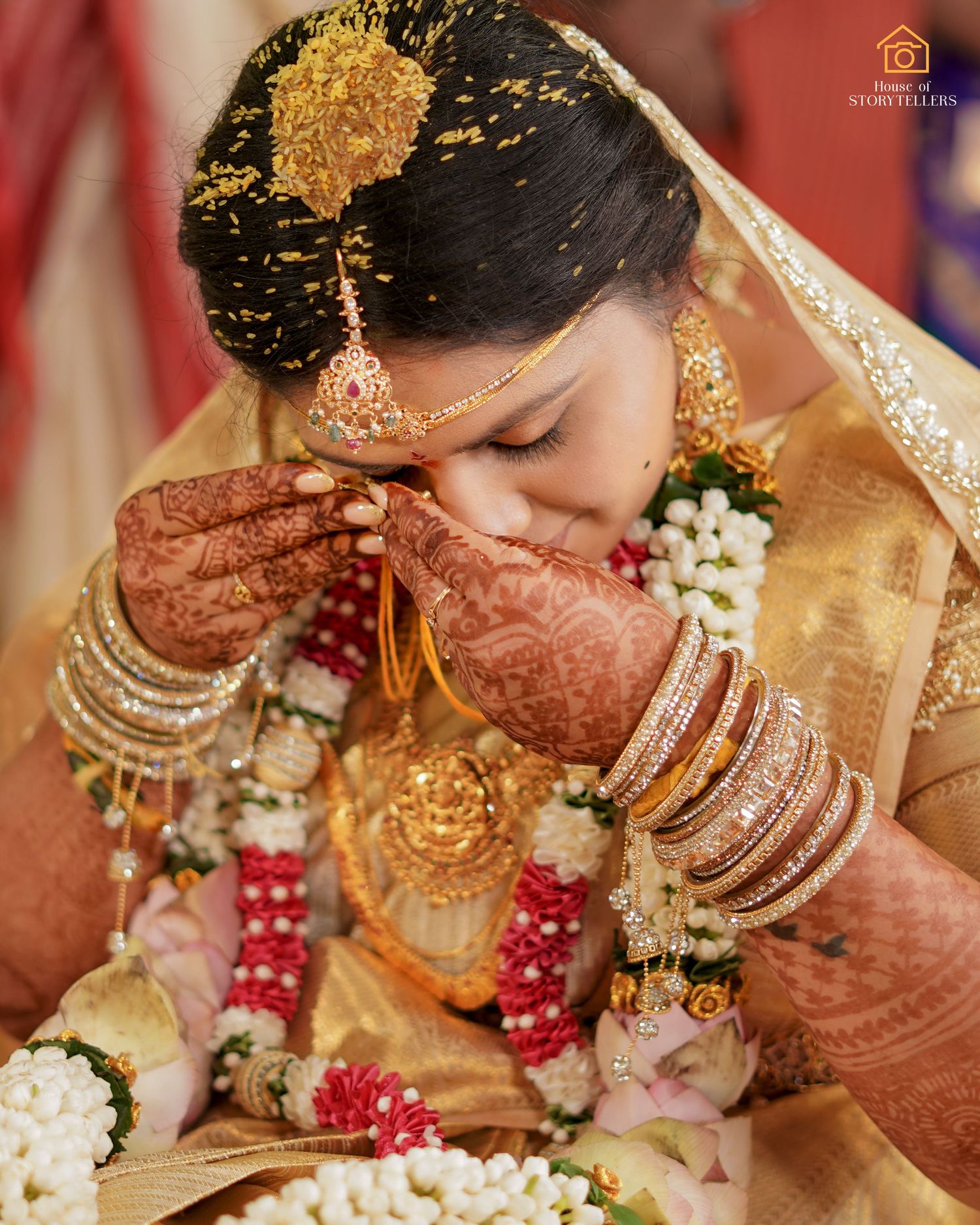 Traditional Indian bride adorned in gold jewelry and intricate henna designs during wedding ceremony.