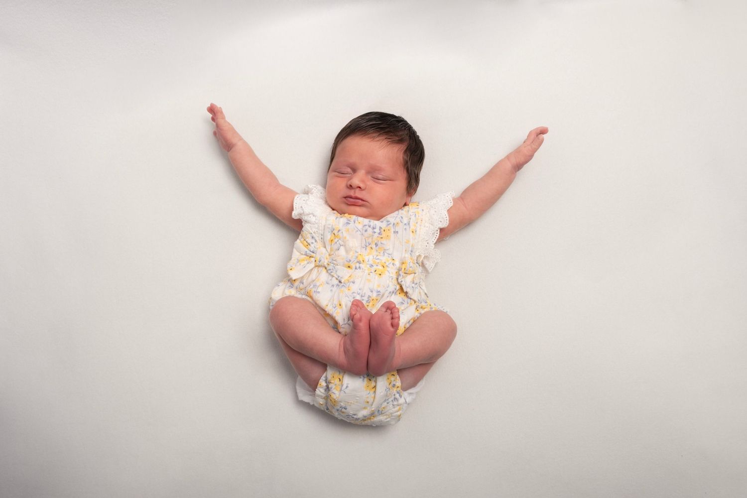 newborn girl with arms spread and feet up having a stretch