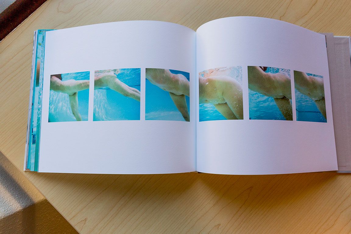 Open photo book displaying sequence of abstract blue and green artistic images spread across two pages.