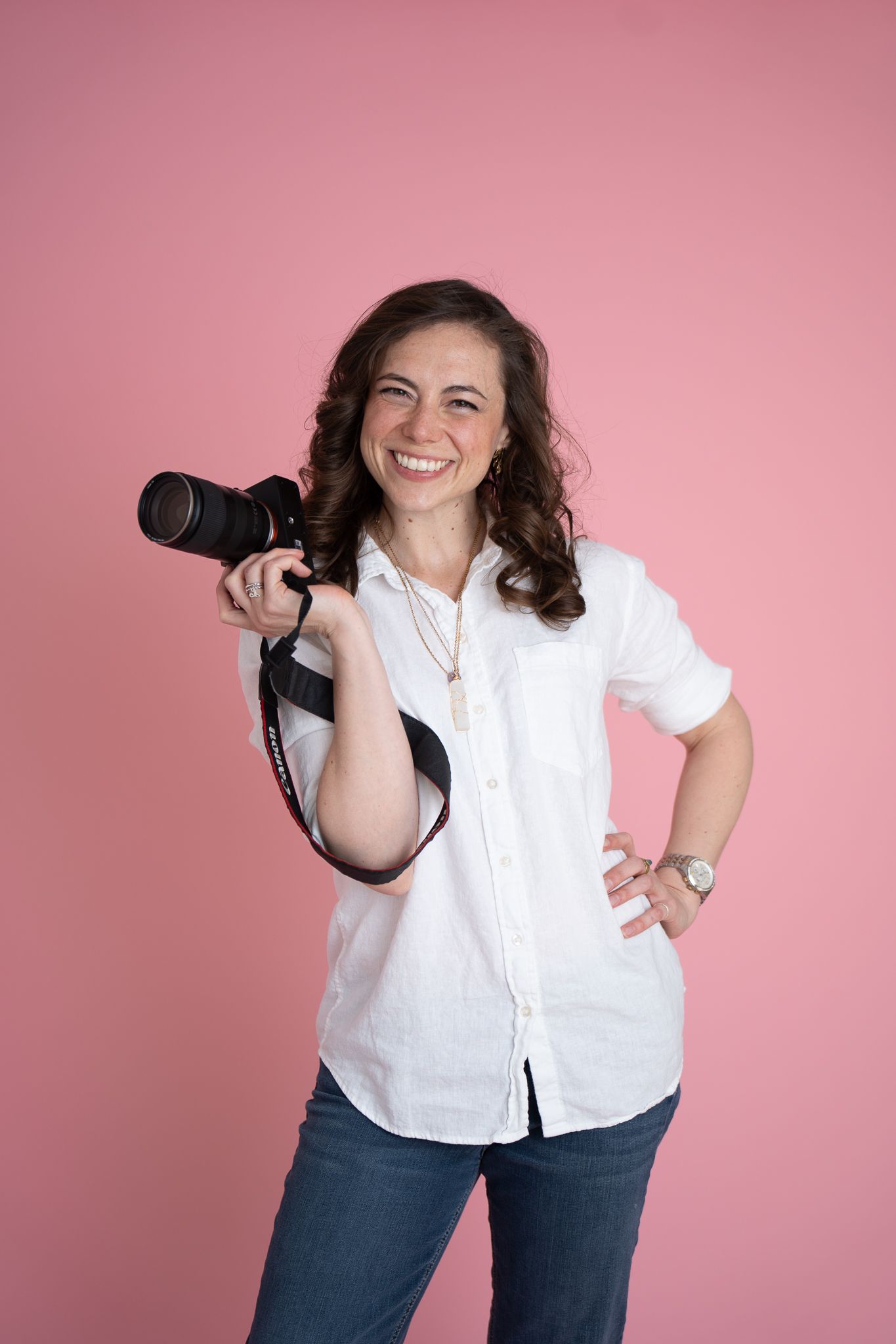 Portrait of woman in black tank top smiling outdoors with natural foliage background.
