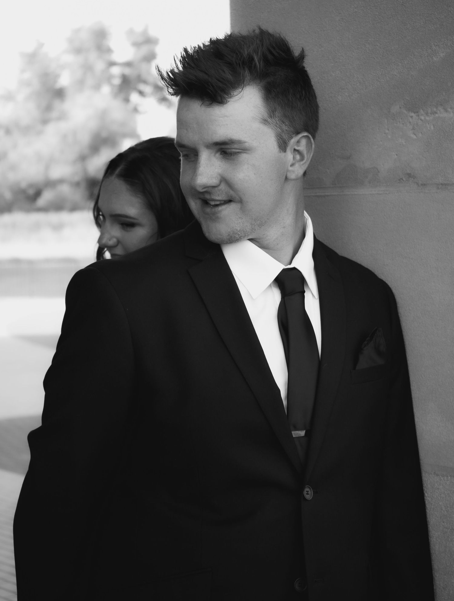 A black and white portrait of a couple in formal attire standing close together.