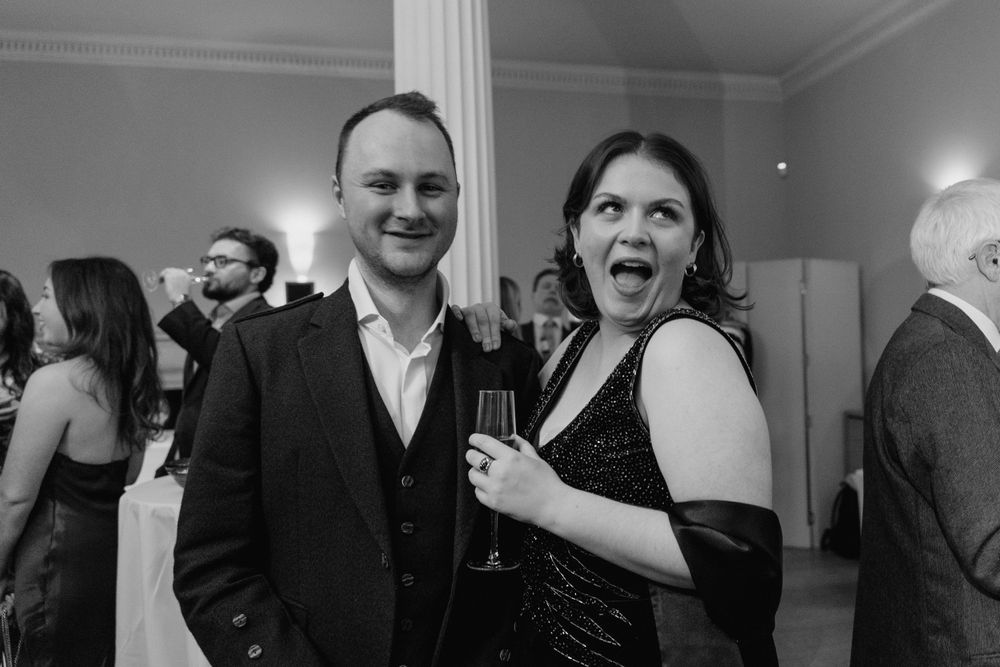 Two guests enjoying drinks and laughter at an elegant evening event.