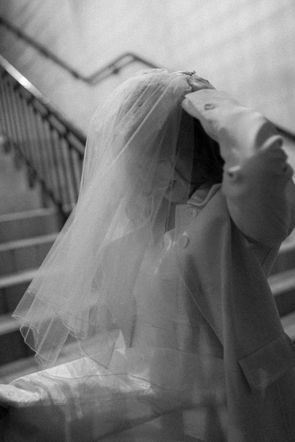 Artistic black and white photo of flowing bridal veil and dress details.