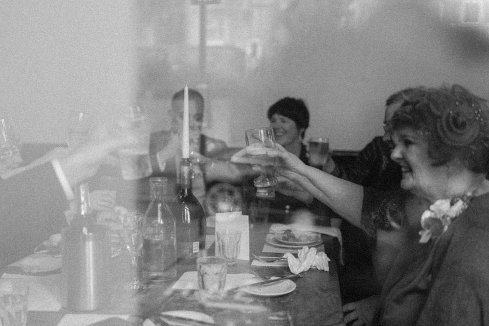 Vintage black and white photo of people toasting at a dinner table.