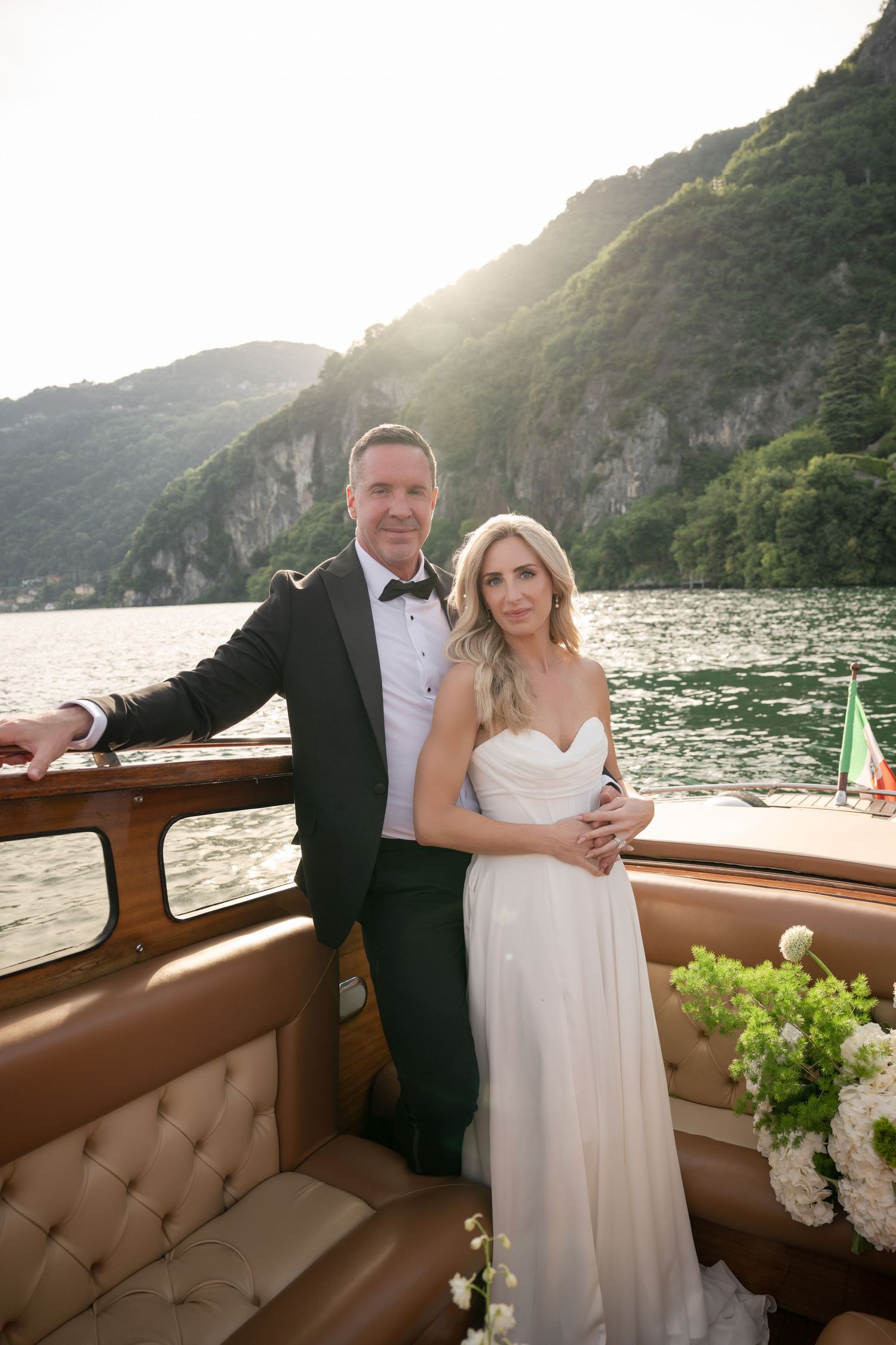 Wedding couple embracing on boat with Positano's picturesque coastal backdrop.