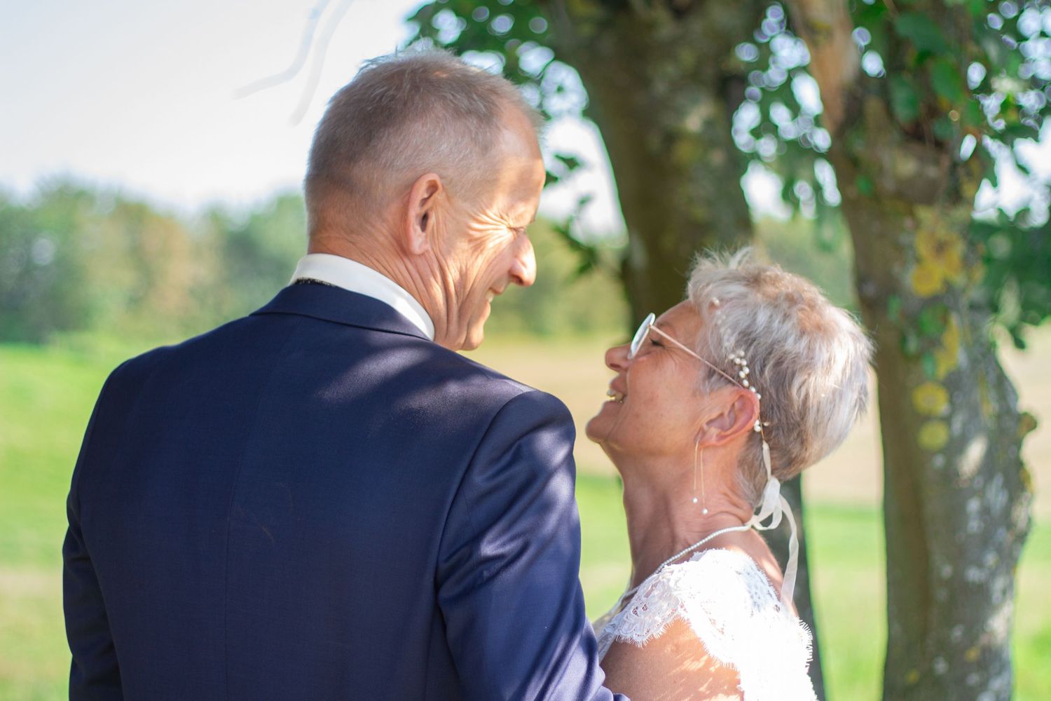 Happy couple sharing joyful moment during outdoor wedding celebration.