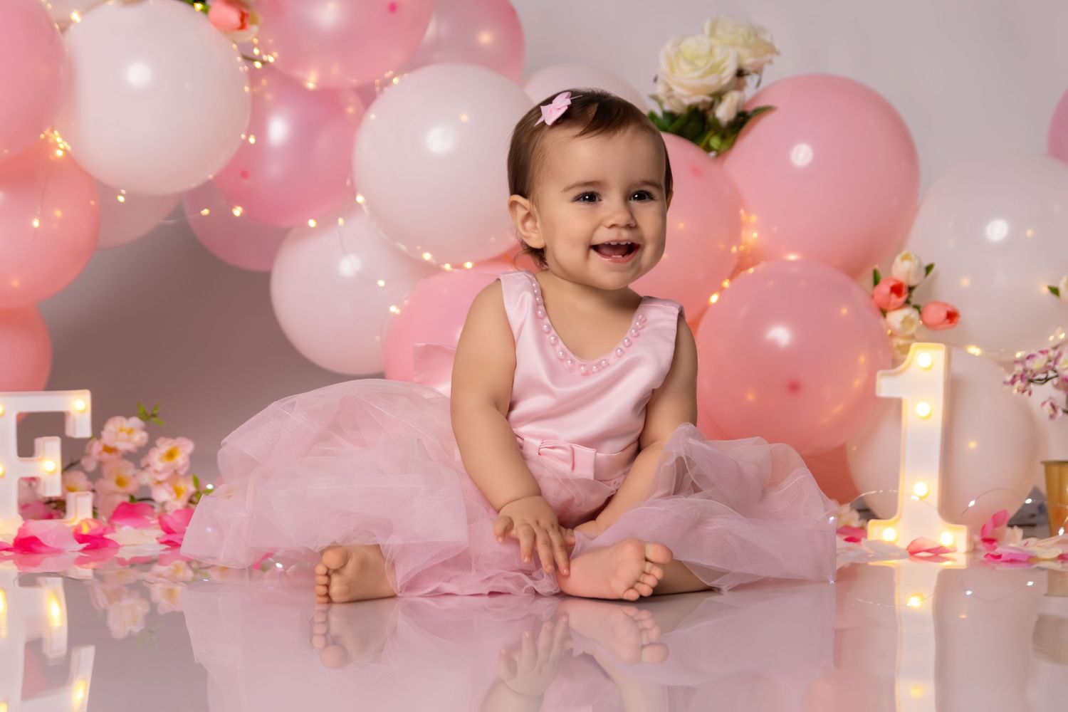 Pink and gold balloon decorations for baby's first birthday cake smash setup.
