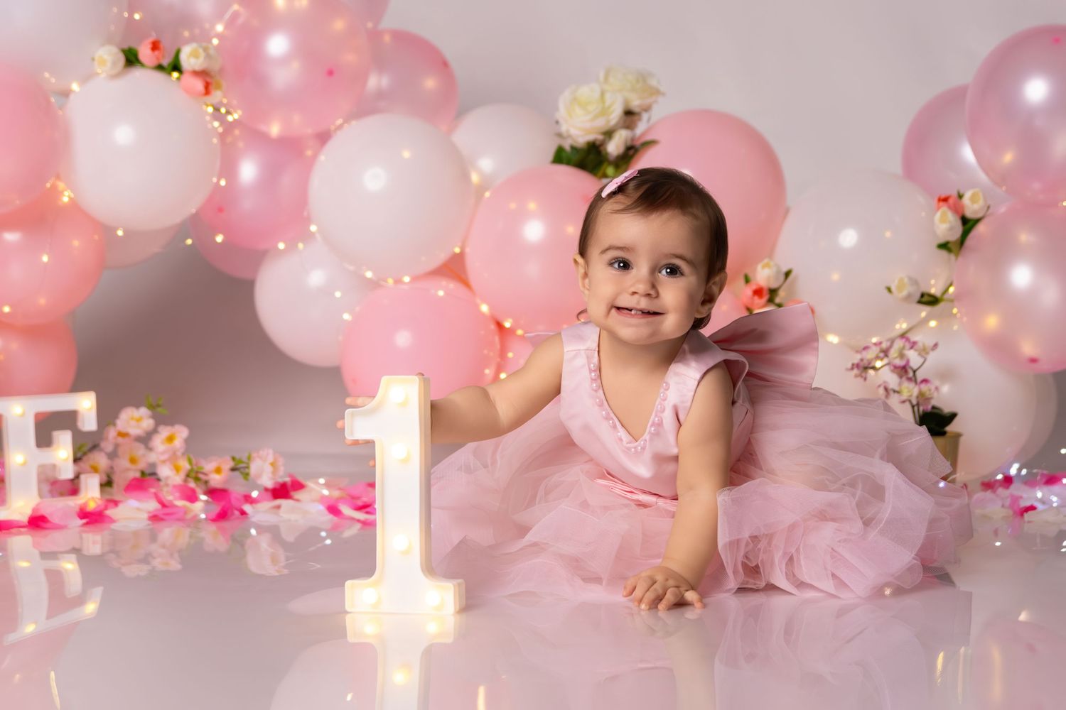 Pink tulle dress and balloons create a magical first birthday celebration scene.