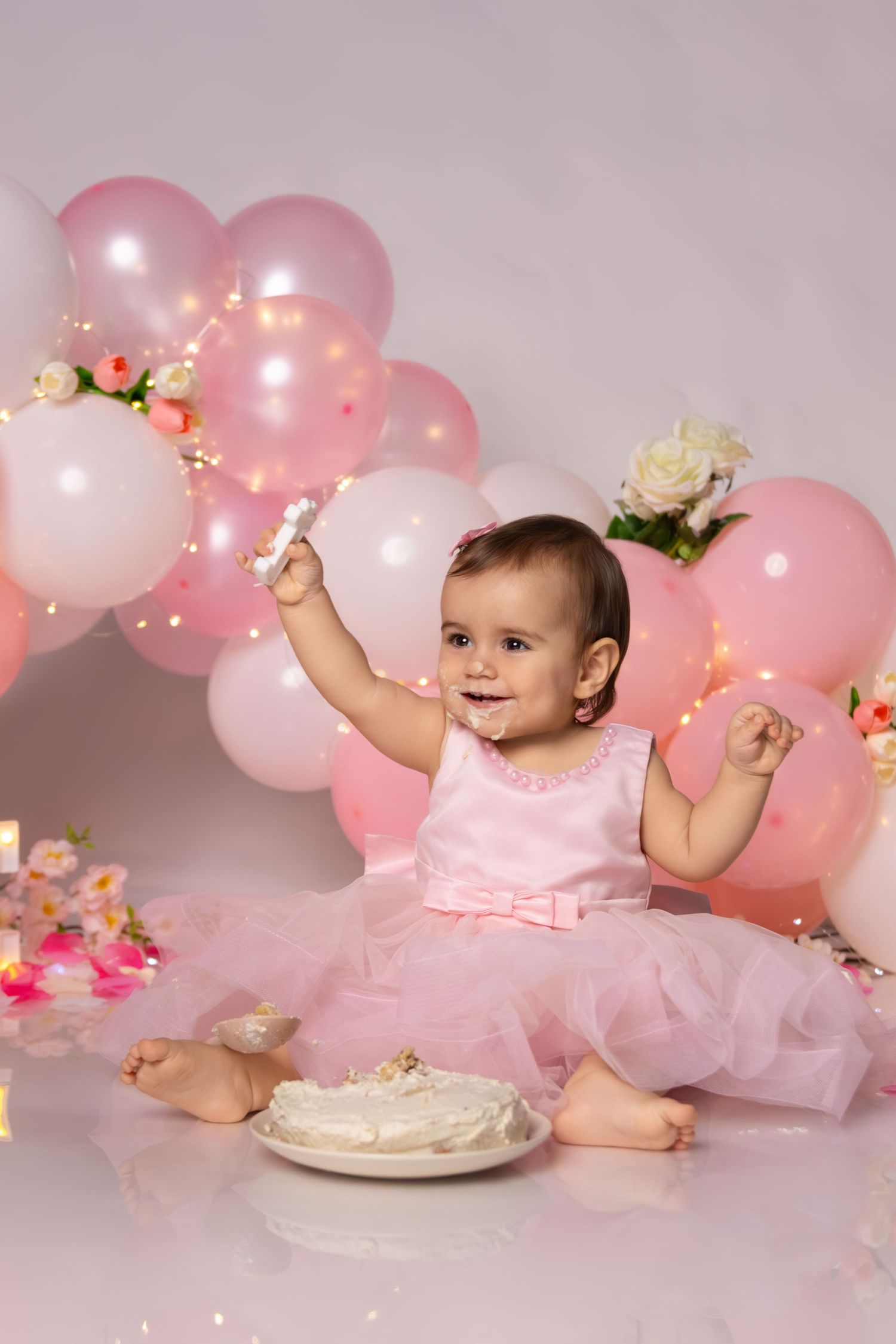 First birthday celebration with white cake, pink tulle dress and balloon decorations.