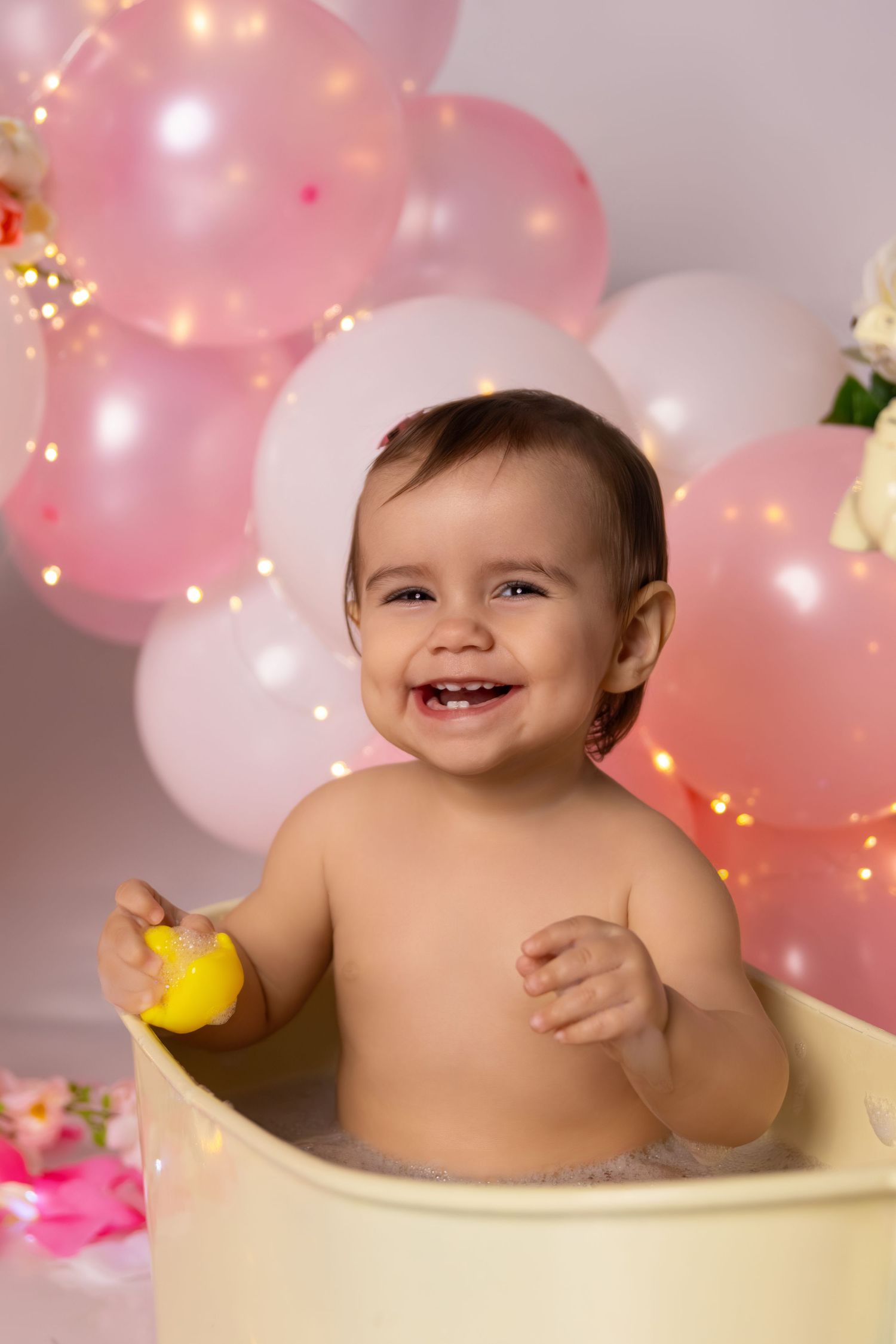 Happy bath time moment captured with yellow duck toy and pink balloon decorations.