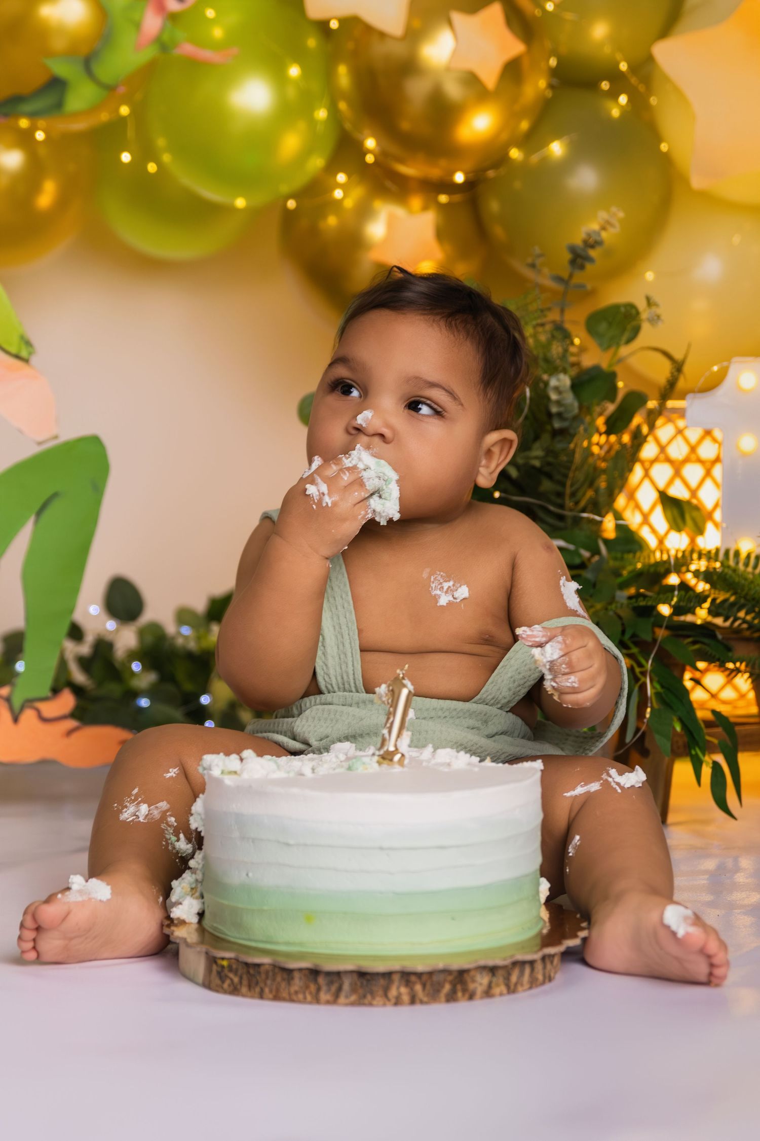 Baby enjoying cake smash session with white and mint green frosting.