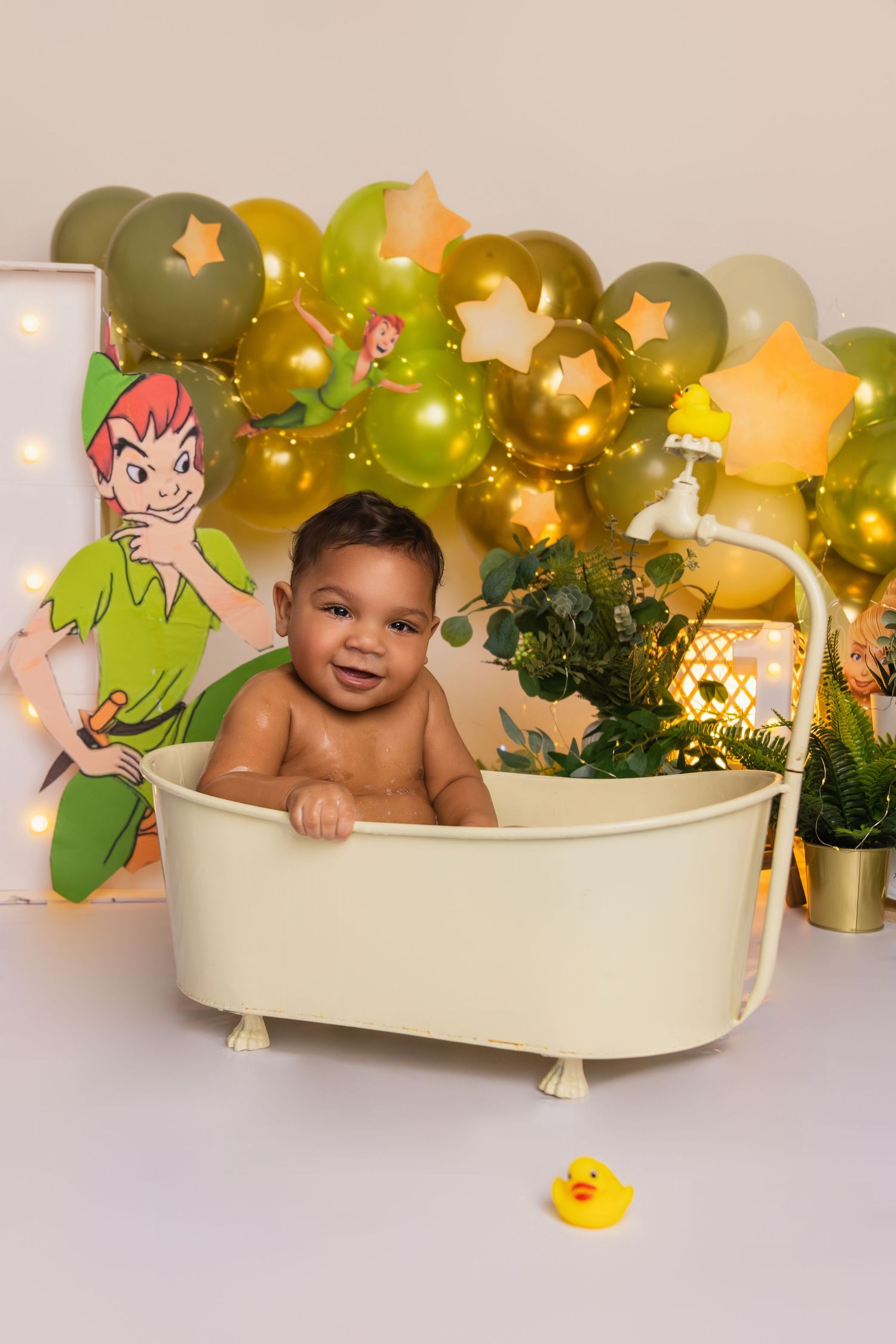 Peter Pan themed photo setup with bathtub prop and green balloon decorations.