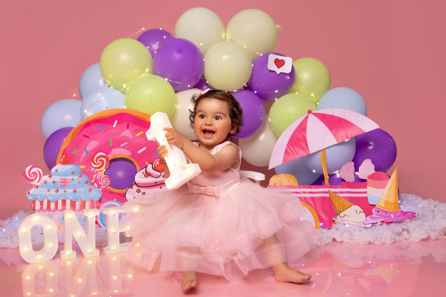 Birthday photography setup with pastel balloons, pink backdrop, and party decorations.