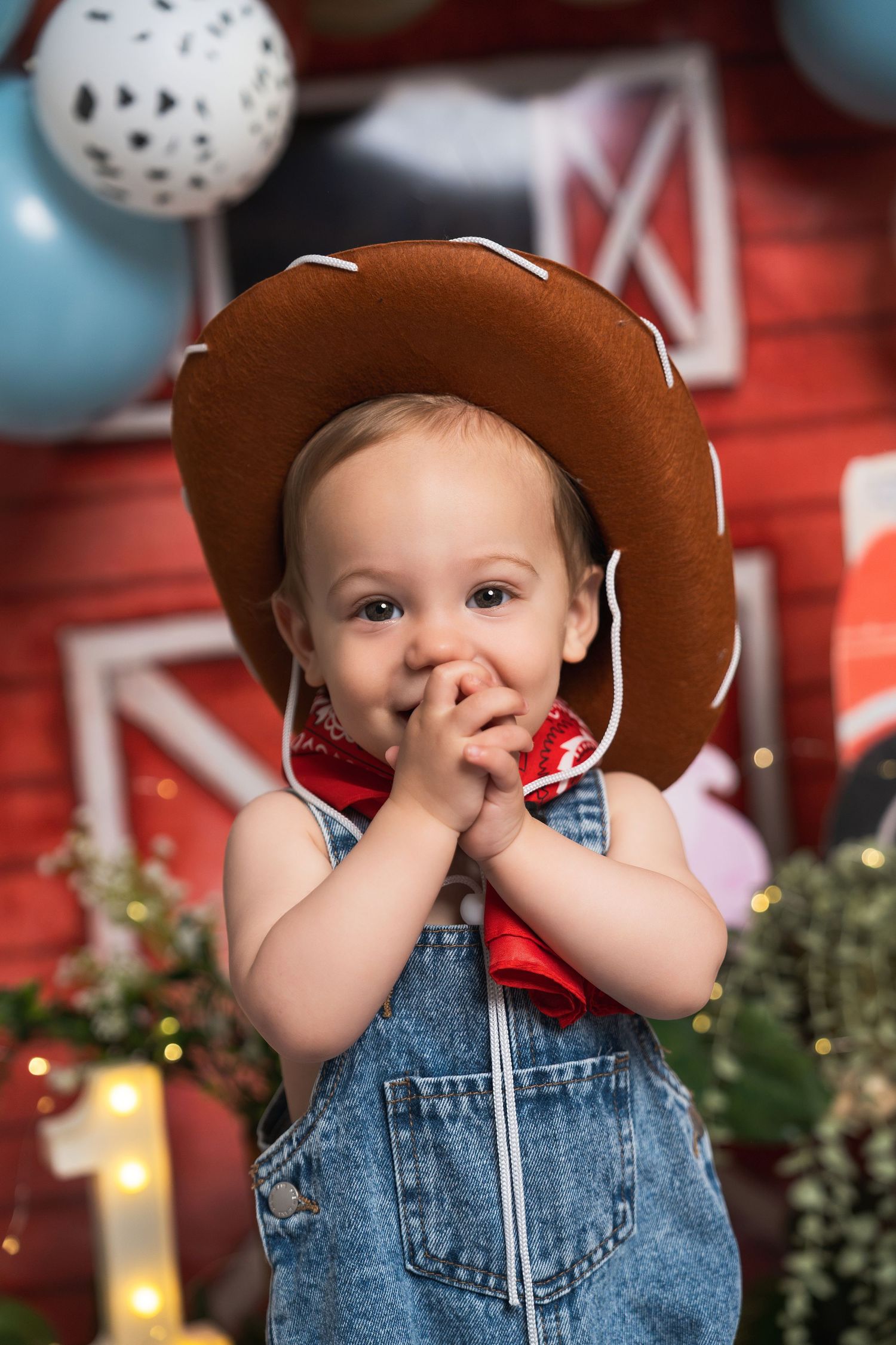 Adorable baby in denim overalls and brown cowboy hat at a western-themed first birthday party.