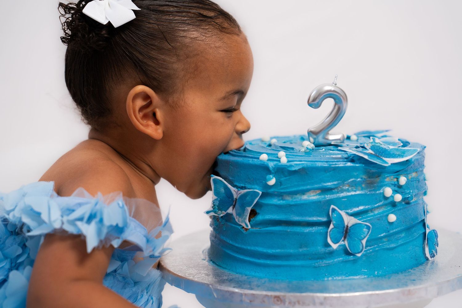 Close-up shots of baby reaching for blue decorated birthday cake.