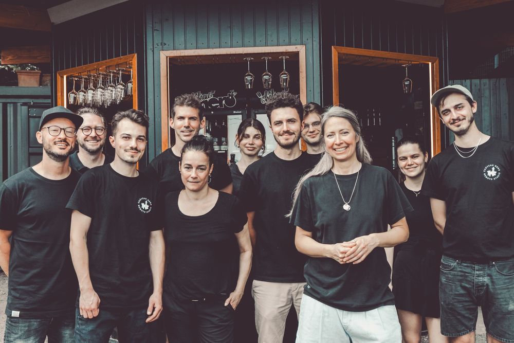 A group of people wearing black clothing pose together in a studio or gym space.