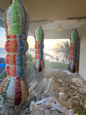 Colorful woven plastic sculptures / columns with debris visible below.