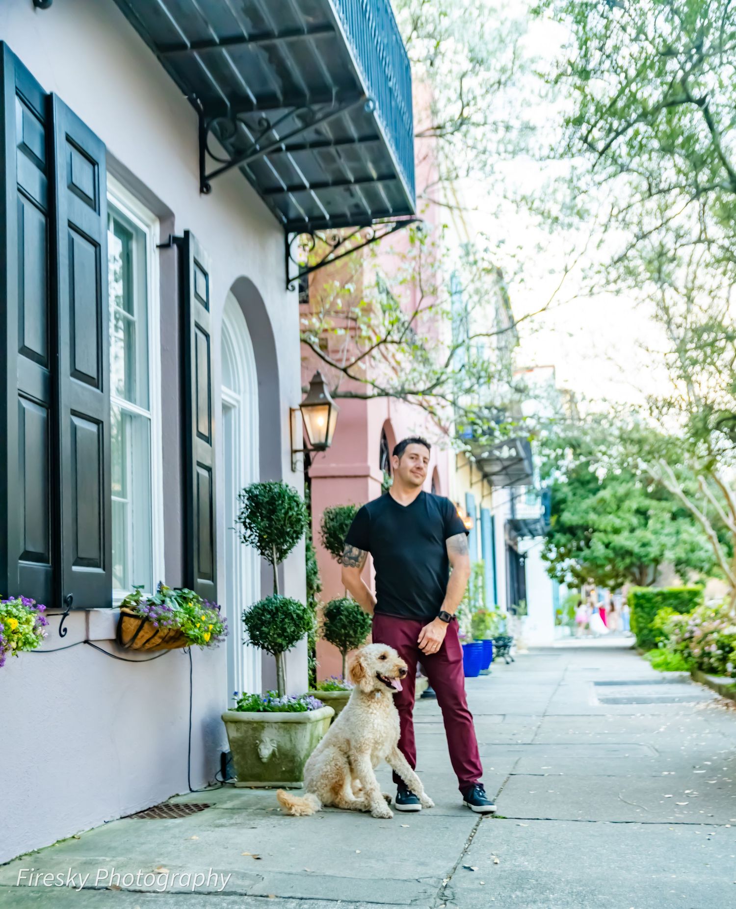A casual street scene with someone and their golden retriever in front of a historic building with window boxes.