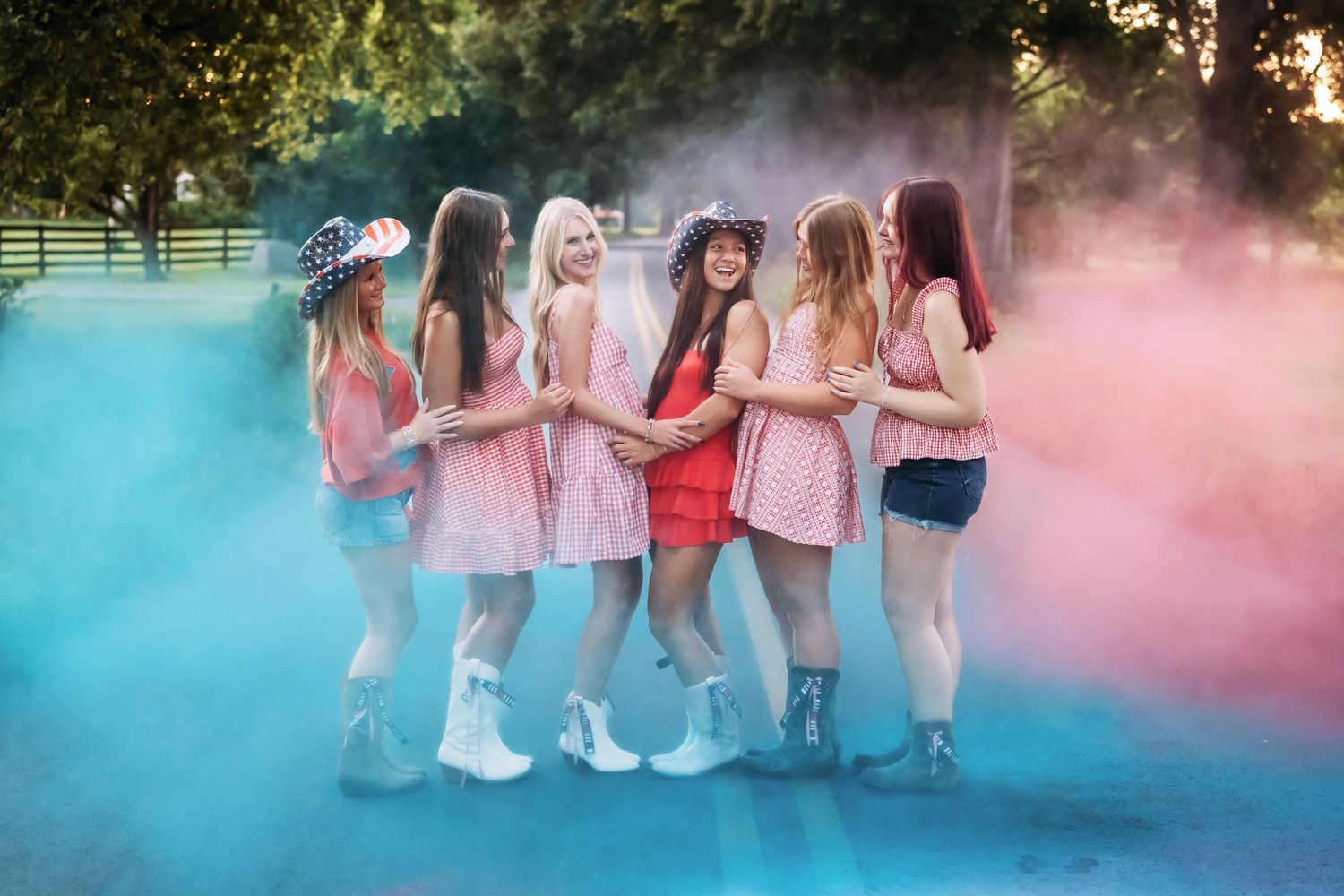 Group of high school senior friends posing together by fountain in casual summer outfits.