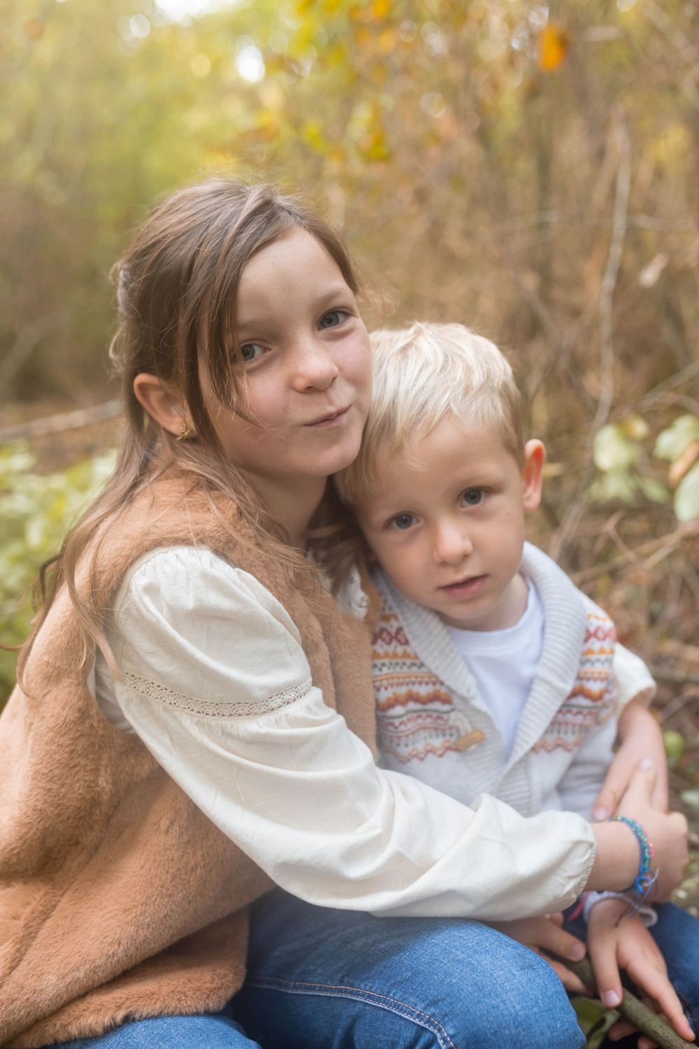 Frère et sœur s'enlaçant avec tendresse lors d'une séance photo en forêt, complicité enfantine capturée par votre photographe niortaise.