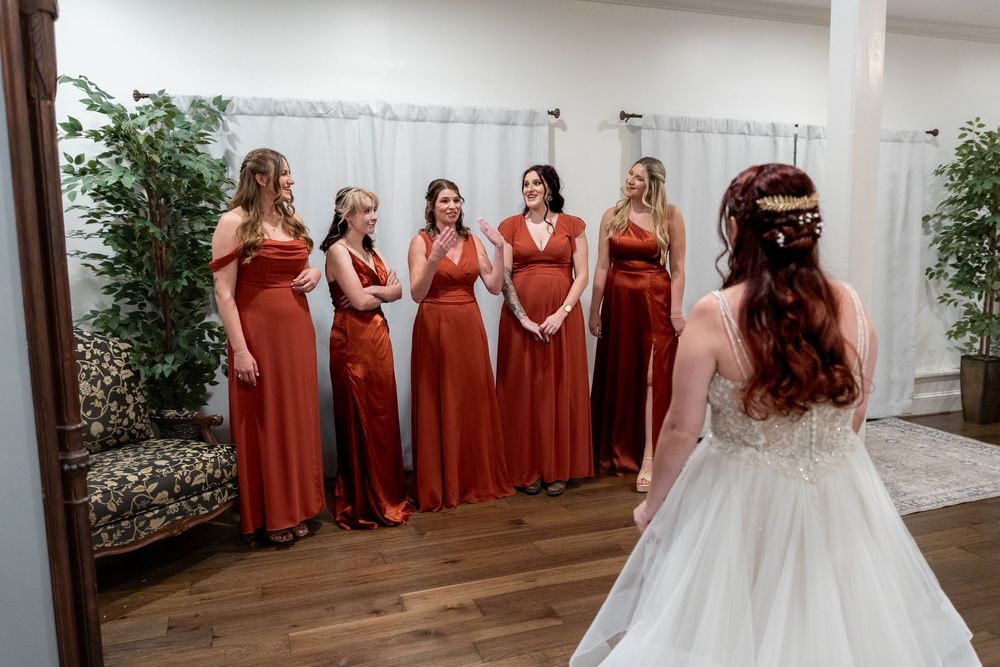 A wedding party poses in a line wearing red bridesmaid dresses and a white wedding gown.