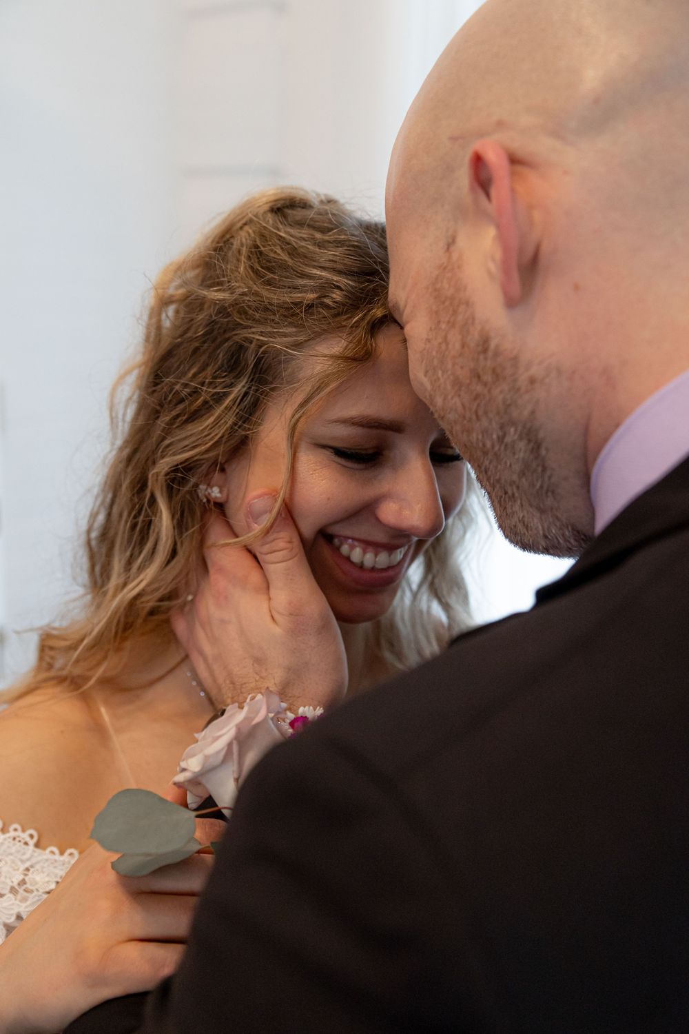An intimate wedding moment showing a couple sharing a tender embrace and joyful smile during their celebration.